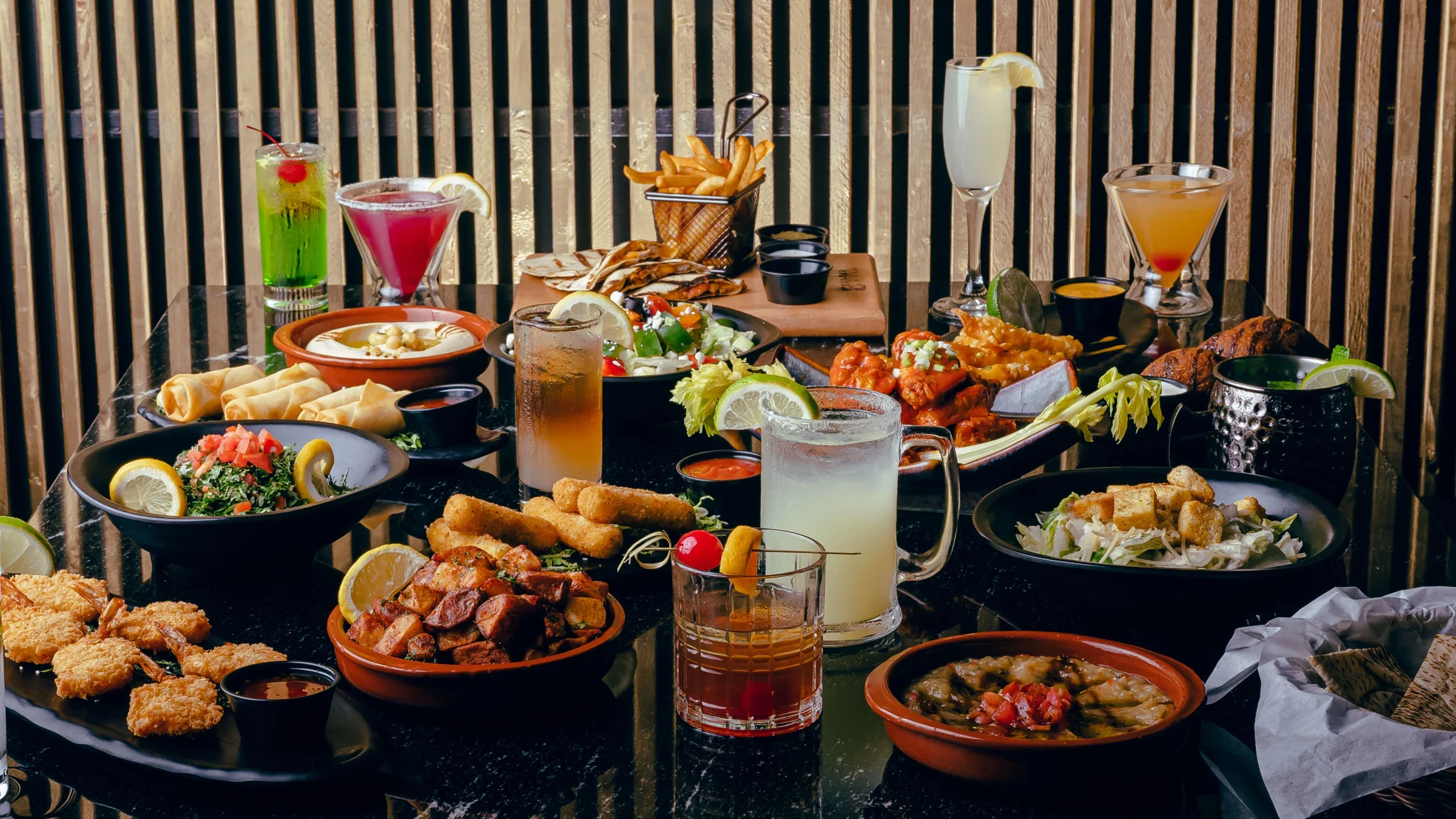 Assorted global dishes and cocktails on a restaurant table