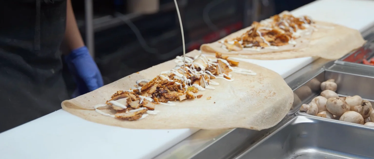 Delicious shawarma wrap being prepared with sauce