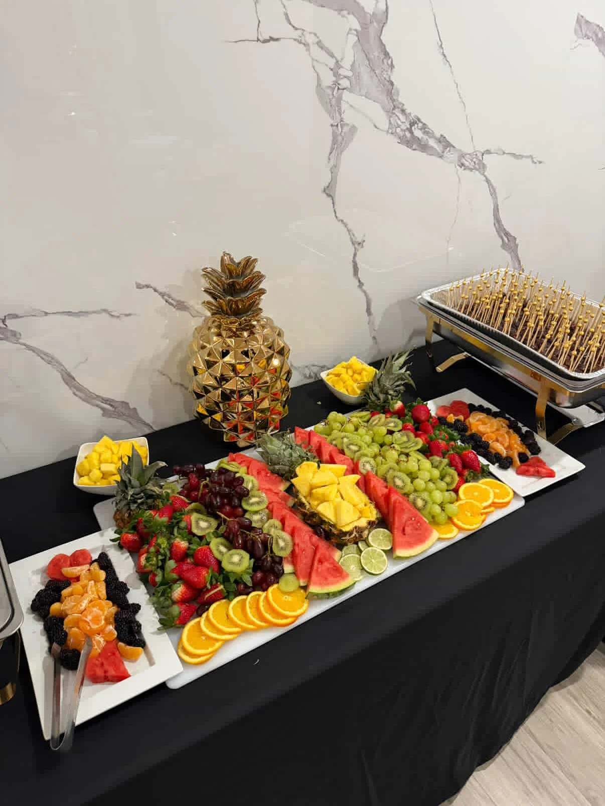 A colorful fruit platter featuring various fruits such as watermelon, pineapple, grapes, oranges, and strawberries, displayed neatly on a table.