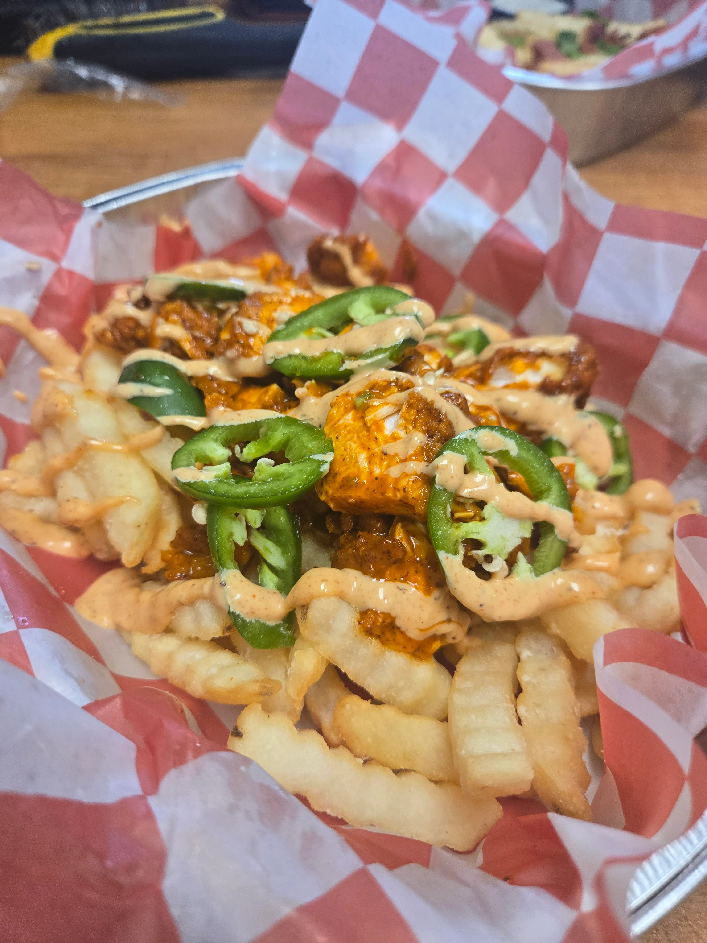 Loaded fries topped with spicy chicken and jalapeños