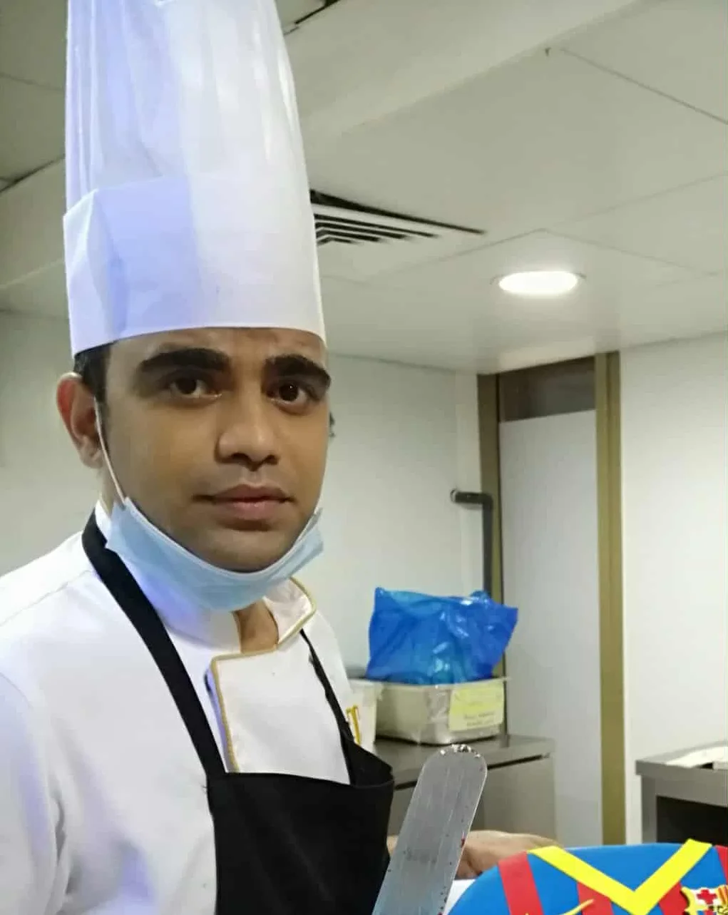Chef presenting a colorful birthday cake in a kitchen