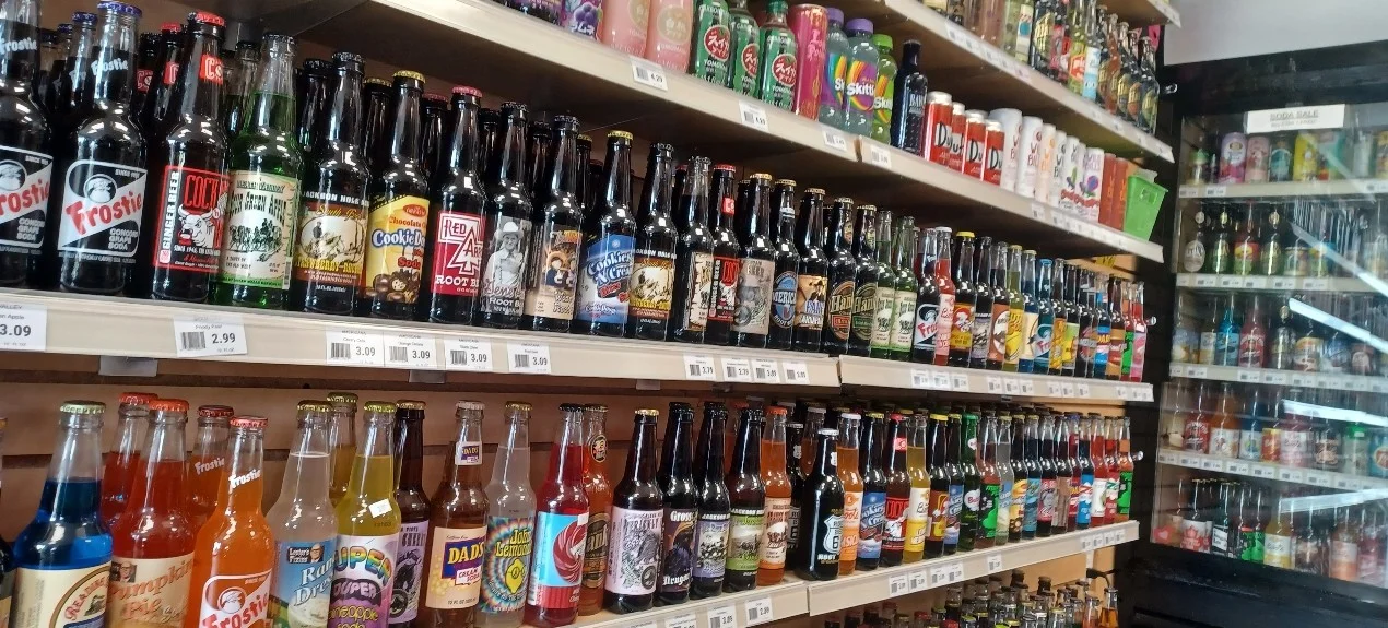 Colorful bottled soda display on shelves in a specialty beverage store