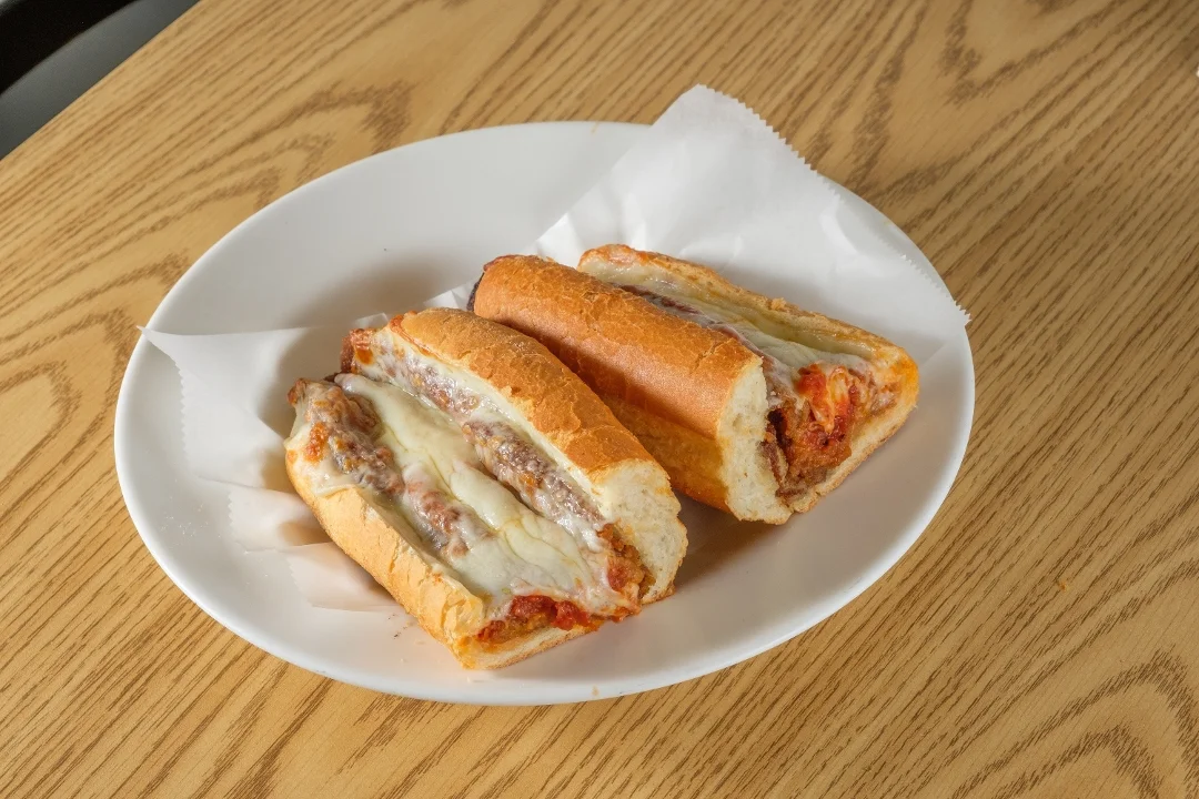 Two sausage and cheese sandwiches served on a plate, with melted cheese oozing from the bread.