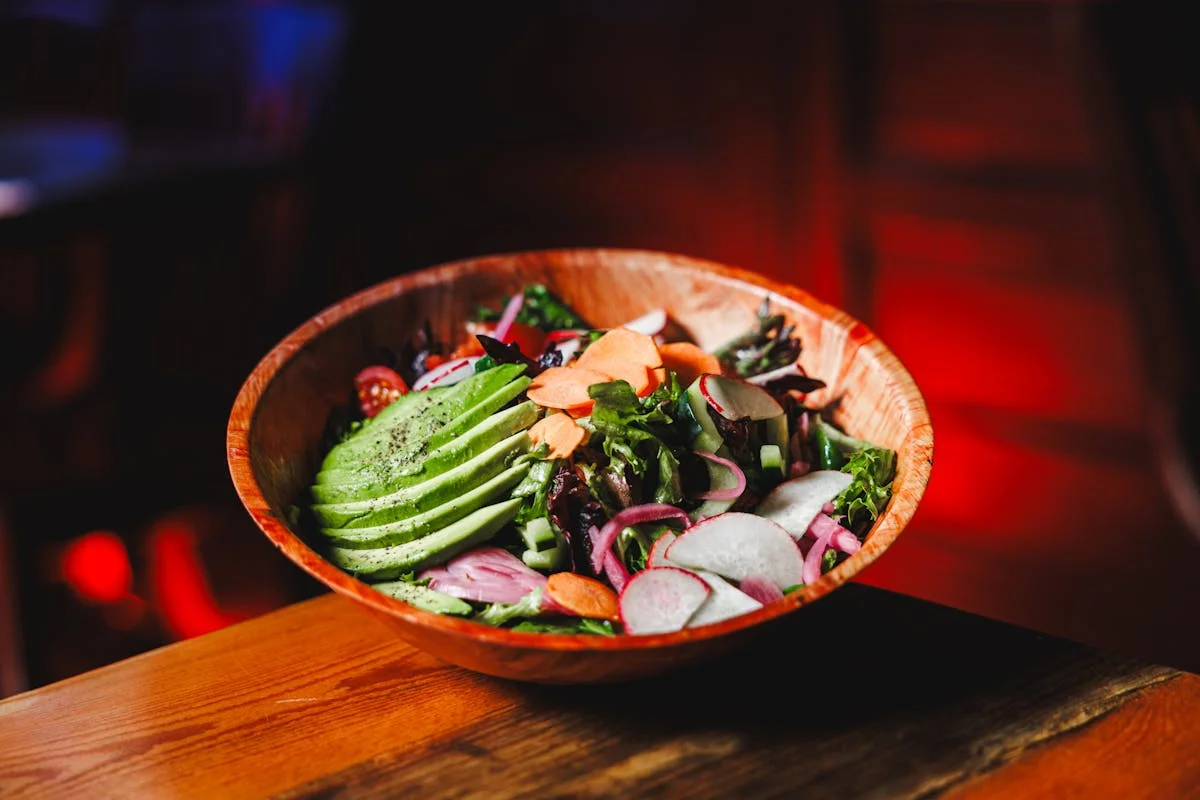 Fresh garden salad with avocado in a wooden bowl