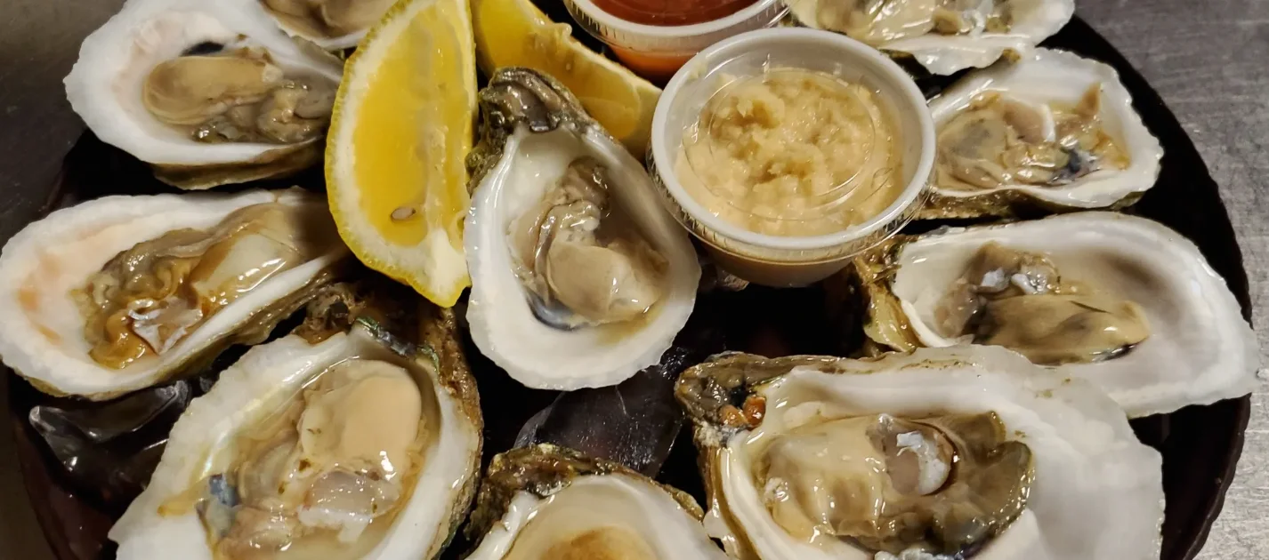 Freshly shucked oysters on a platter with lemon and sauces