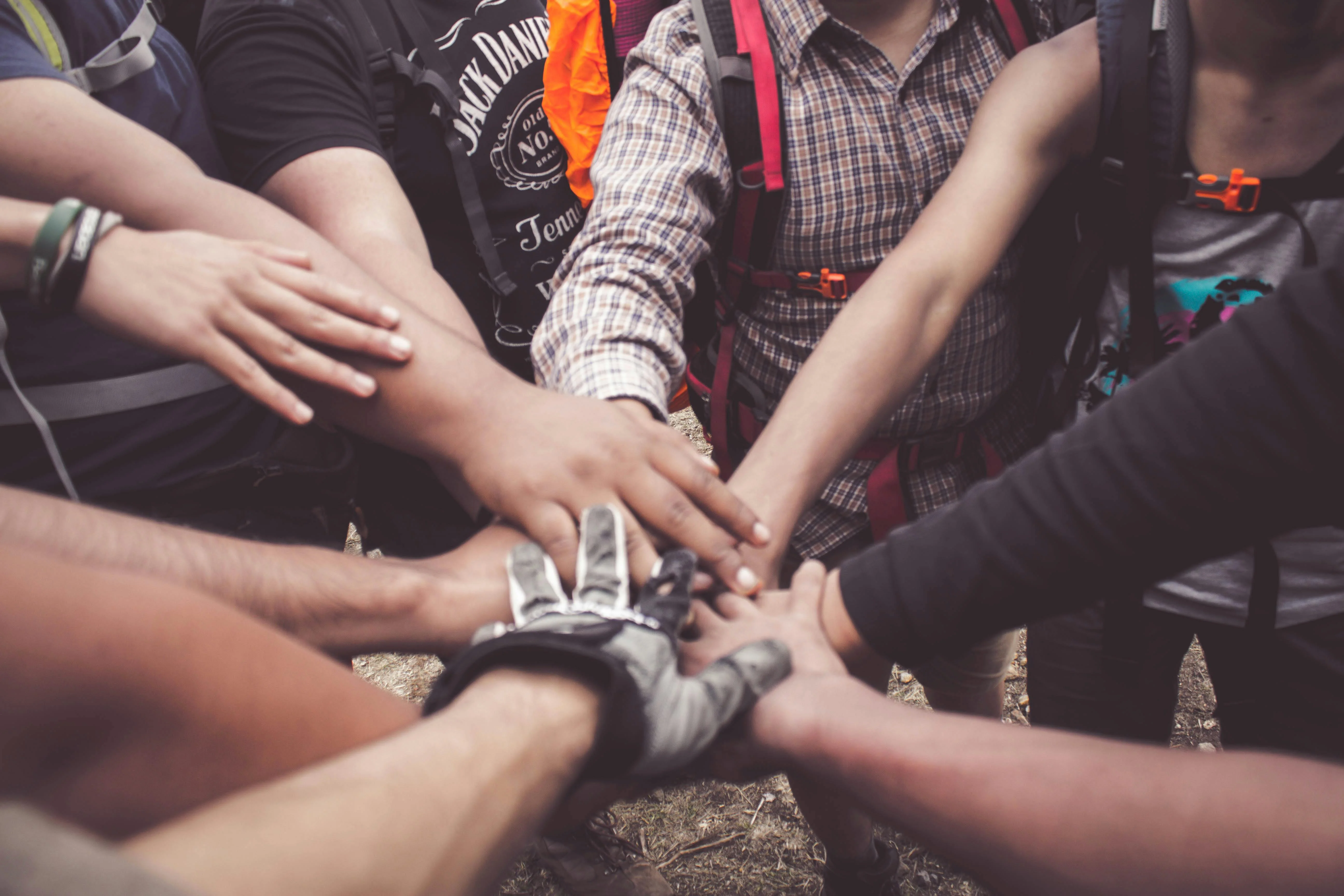 Group of friends joining hands in unity outdoors
