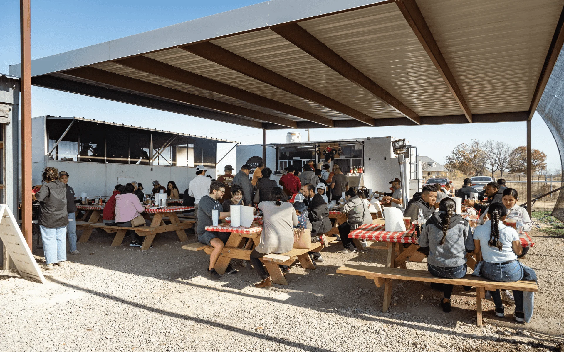 Outdoor dining area with patrons enjoying food at picnic tables