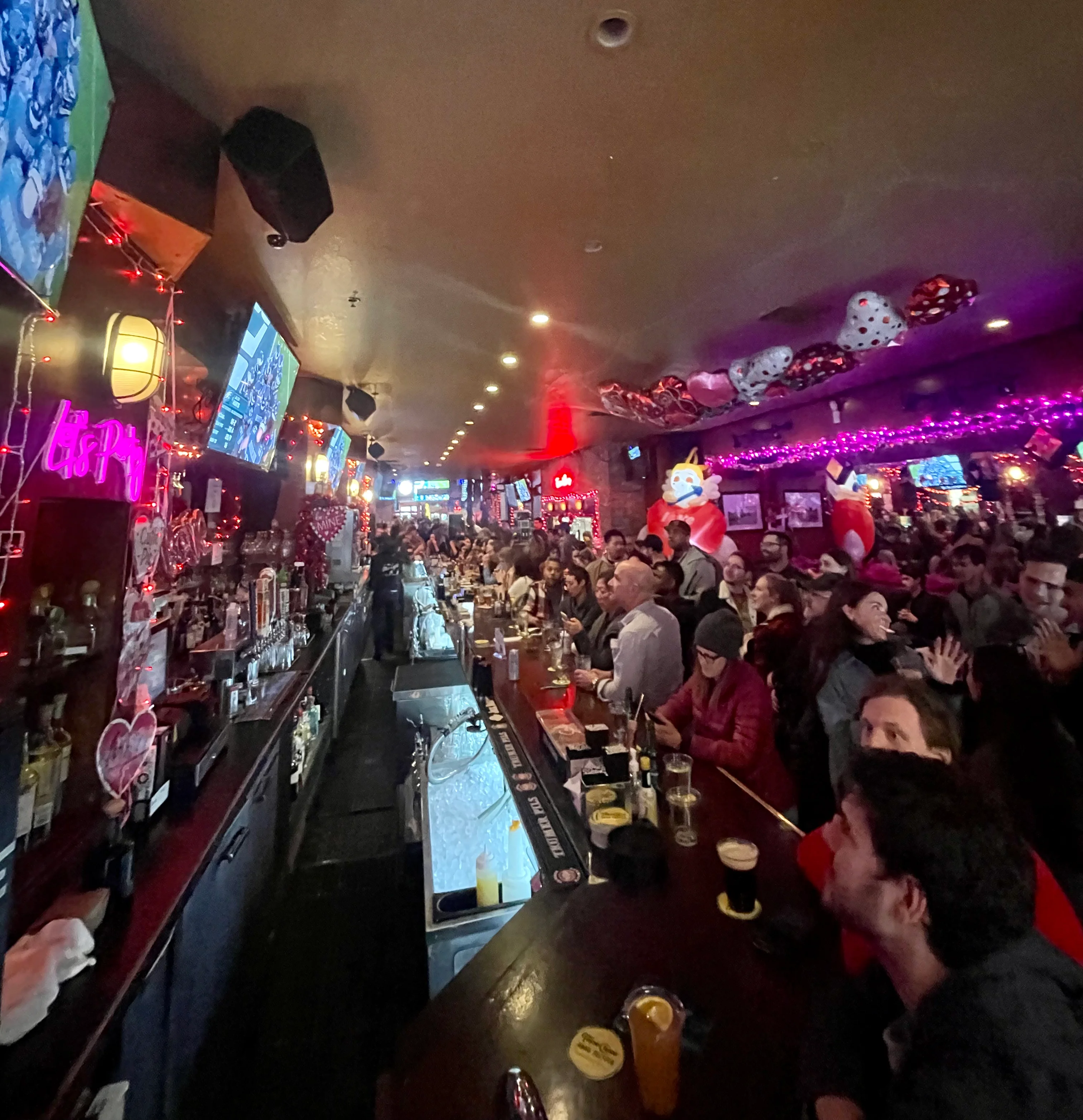 Lively bar scene with patrons enjoying drinks and watching sports on TV