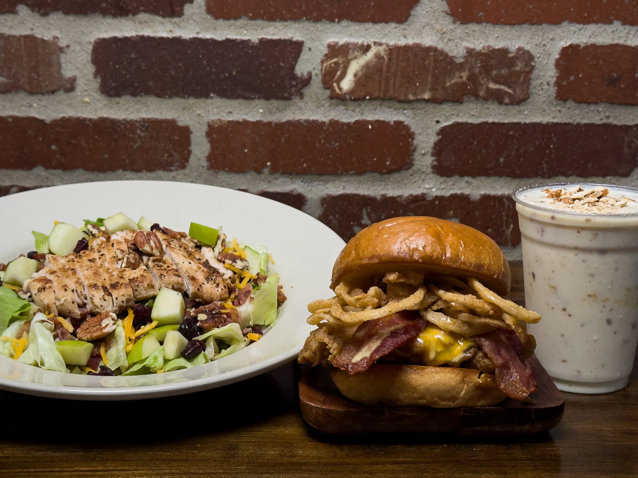 Two gourmet burgers with toppings on a wooden board, served with fries.