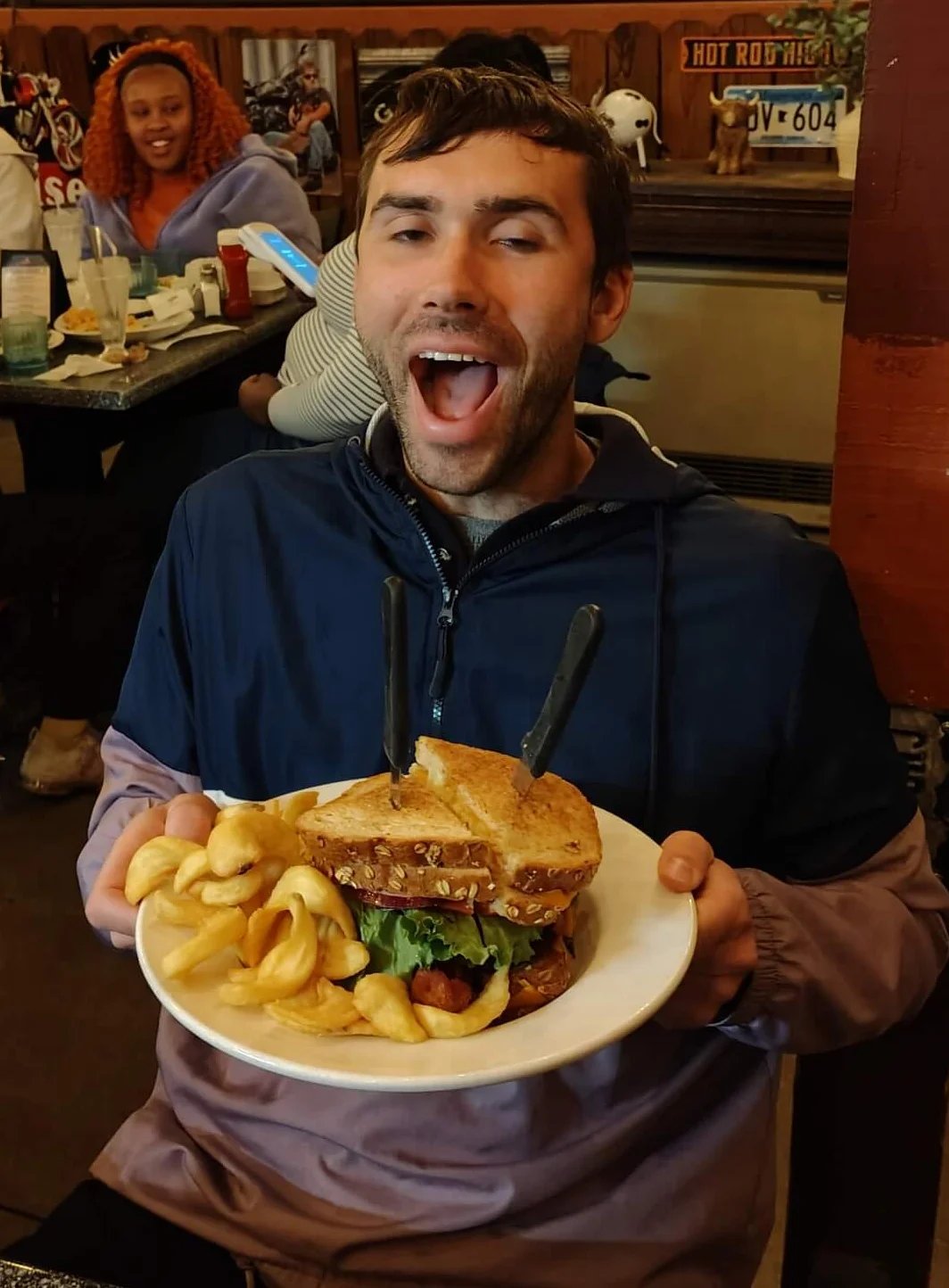 Giant cheeseburger with curly fries in a lively restaurant setting