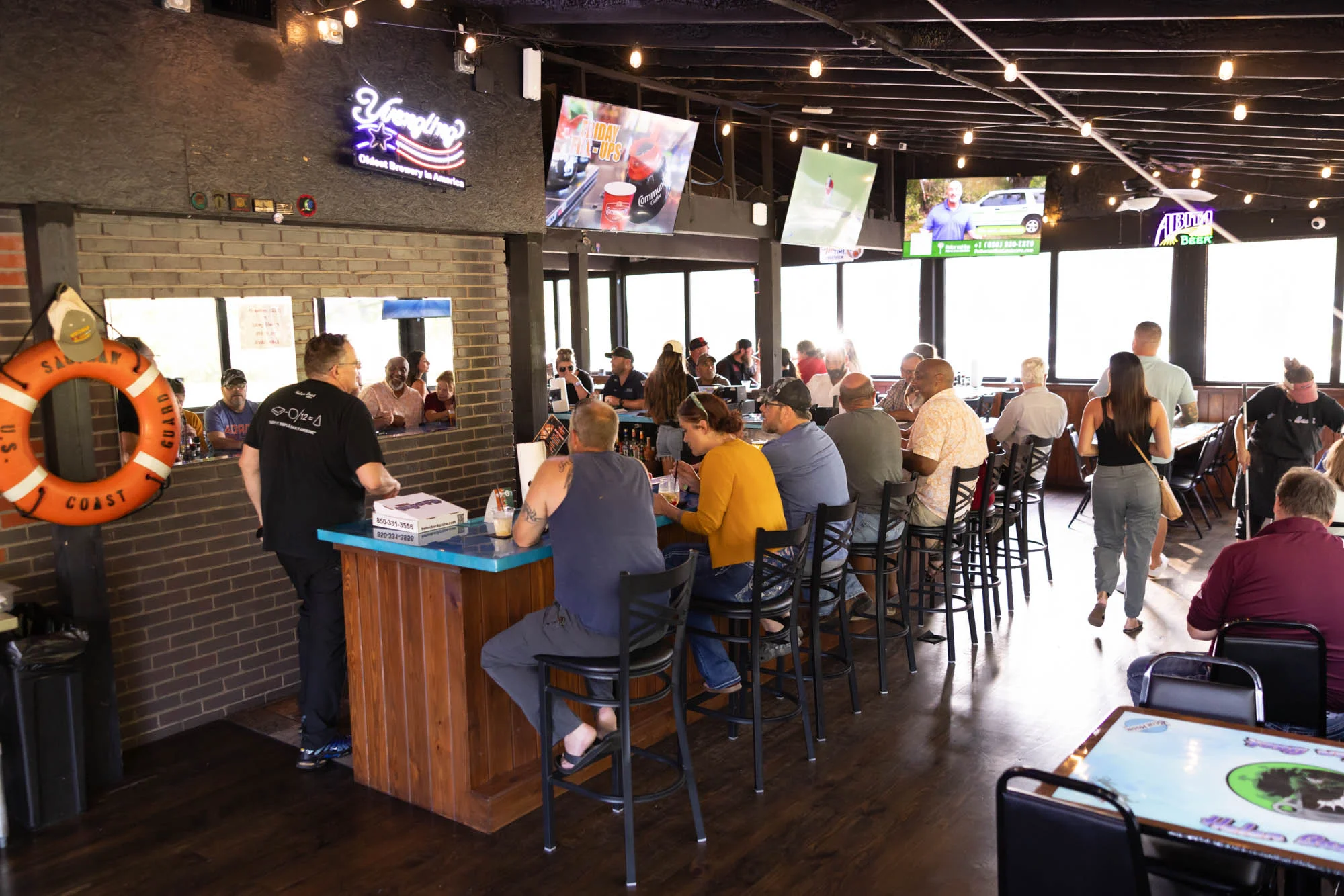 Lively restaurant interior with patrons enjoying food and drinks at the bar