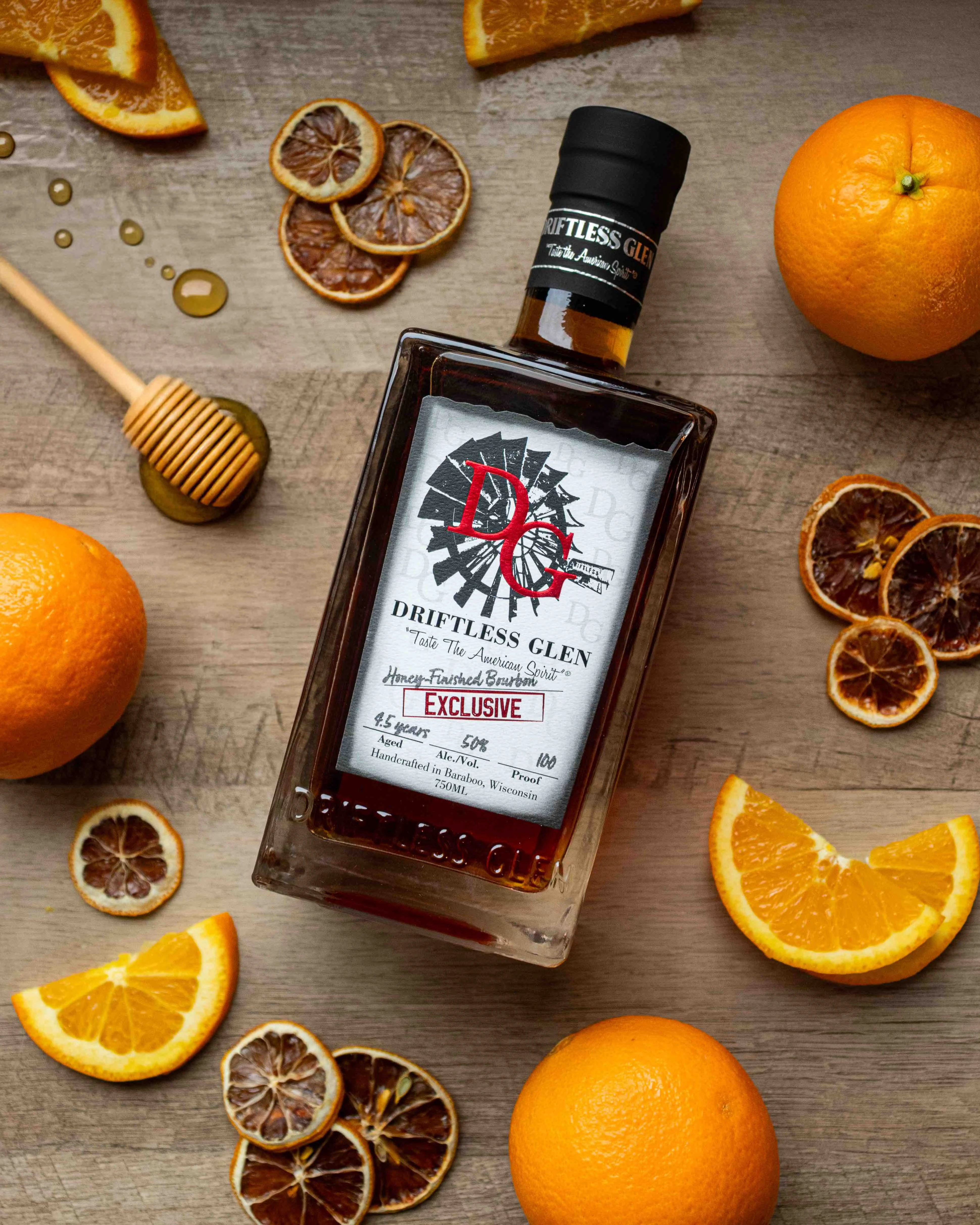 A bottle of Honey-Finished Bourbon with some orange slices and a drip of honey