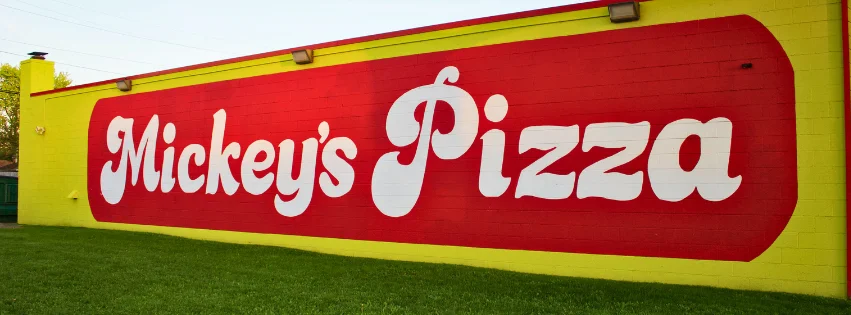 Mural of Mickey's Pizza on a bright yellow wall