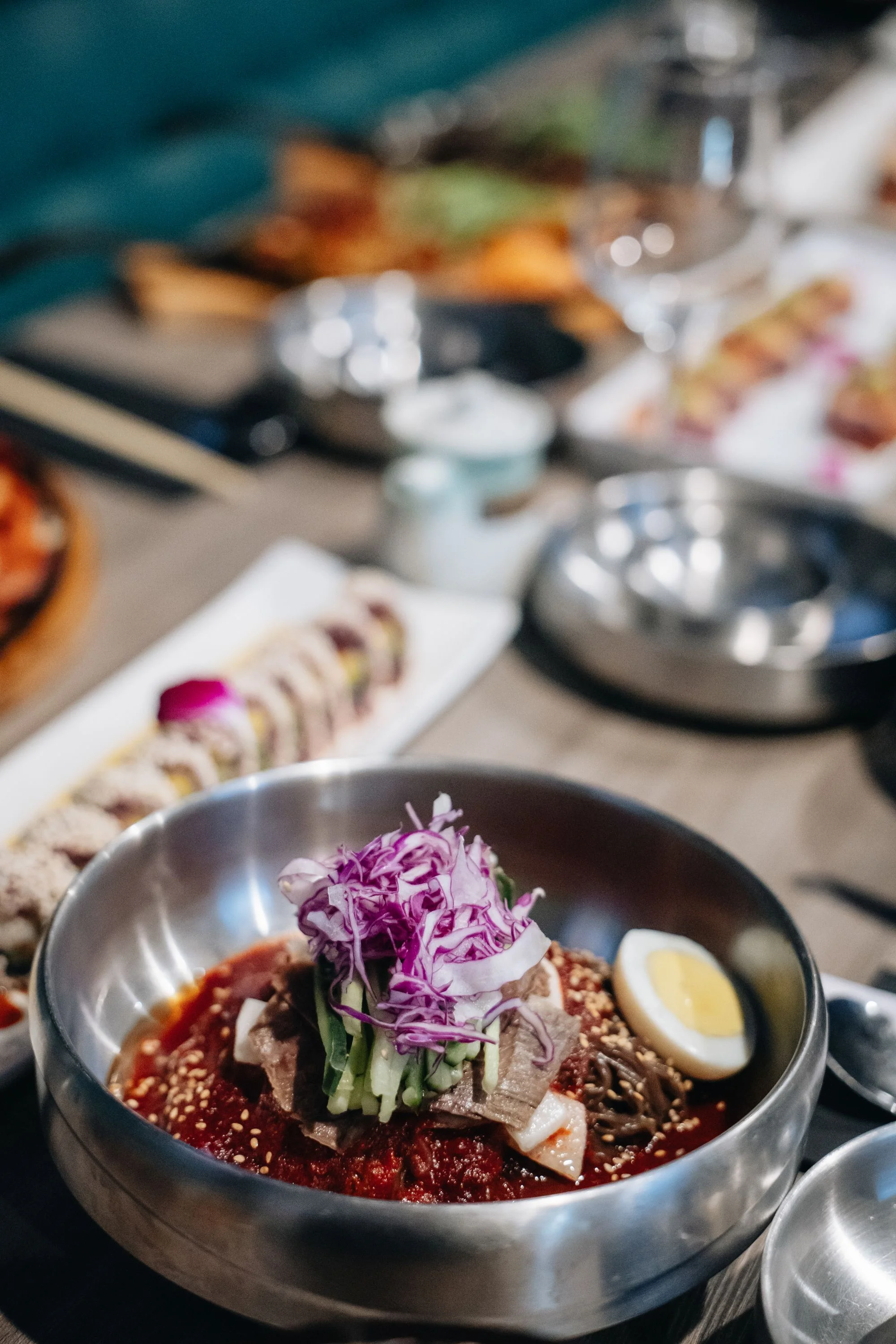 A bowl of colorful Korean dish with vegetables and egg on top.