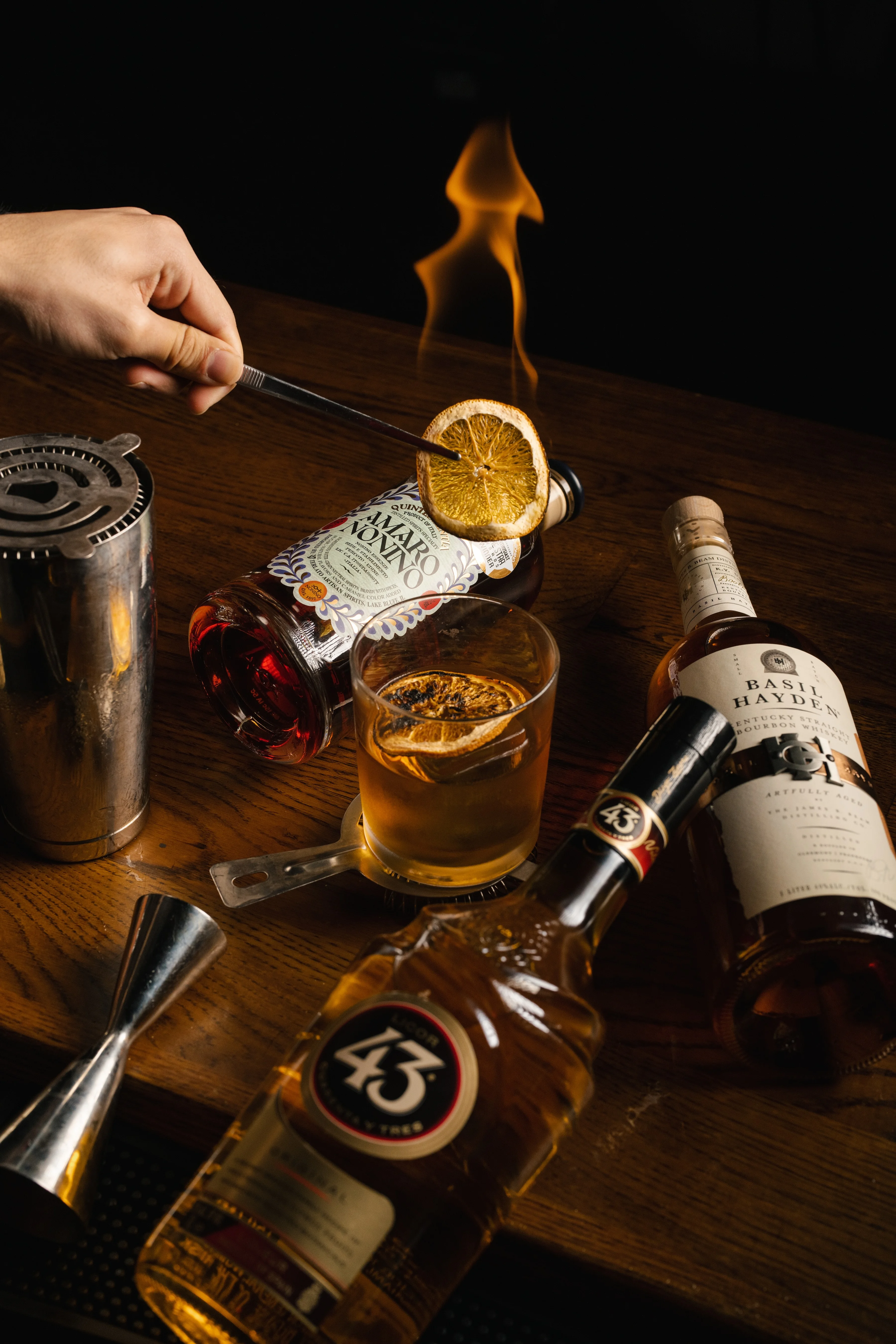 Bartender igniting a cocktail with a dried orange slice