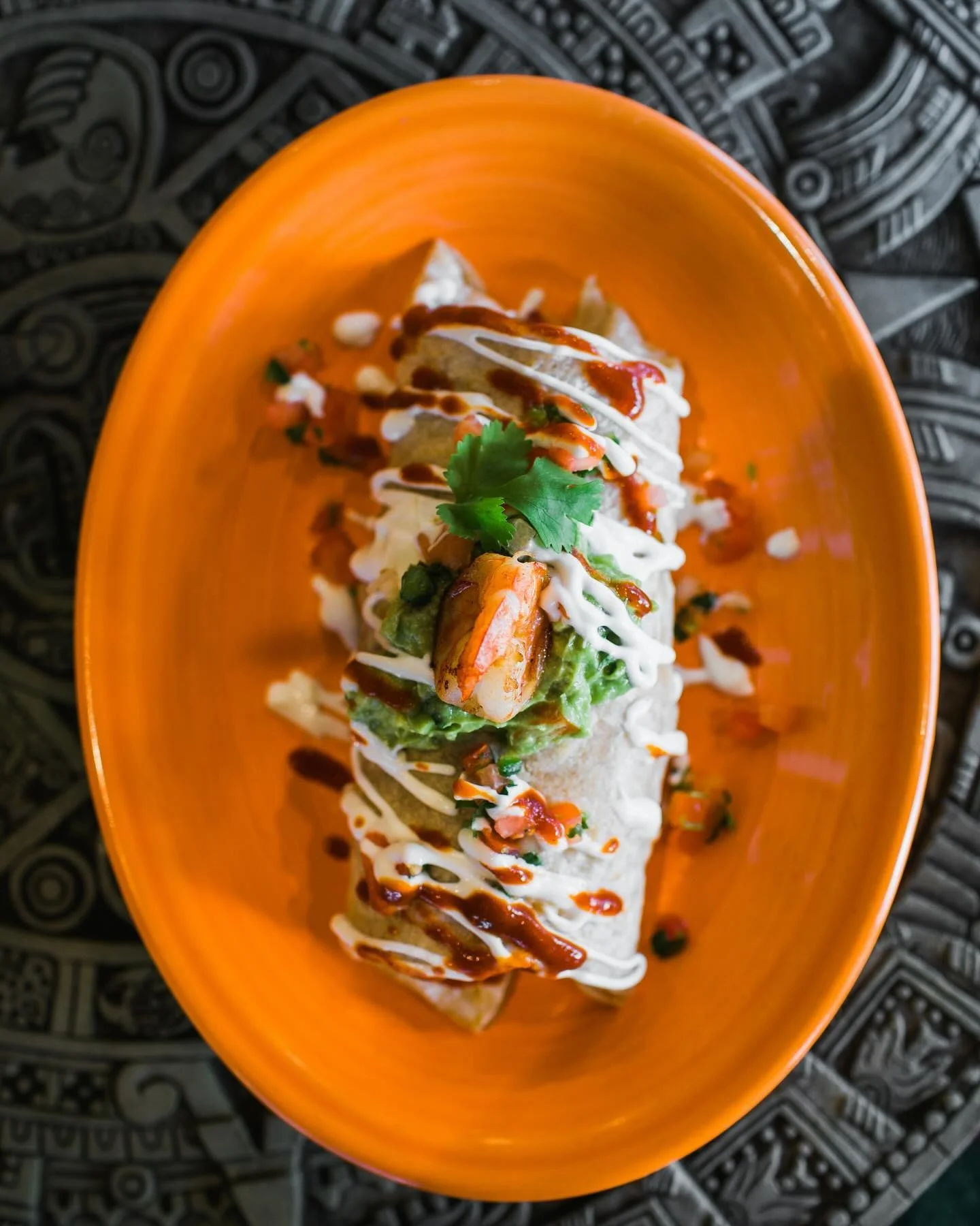 Aztec on Broadway Mexican Restaurant Portland - Burrito with guacamole and sauces on orange plate