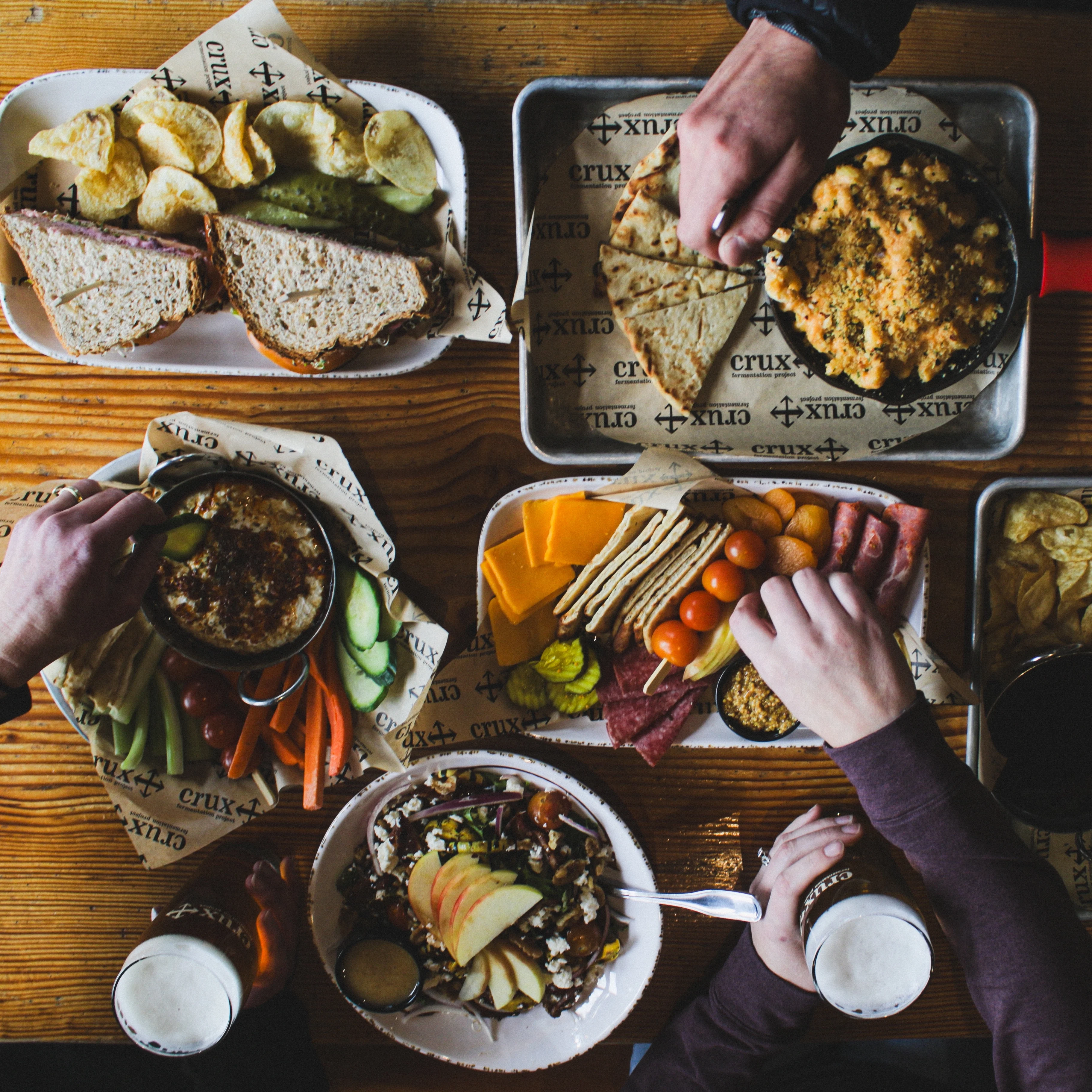 A table set with hands reaching for food in a restaurant setting.