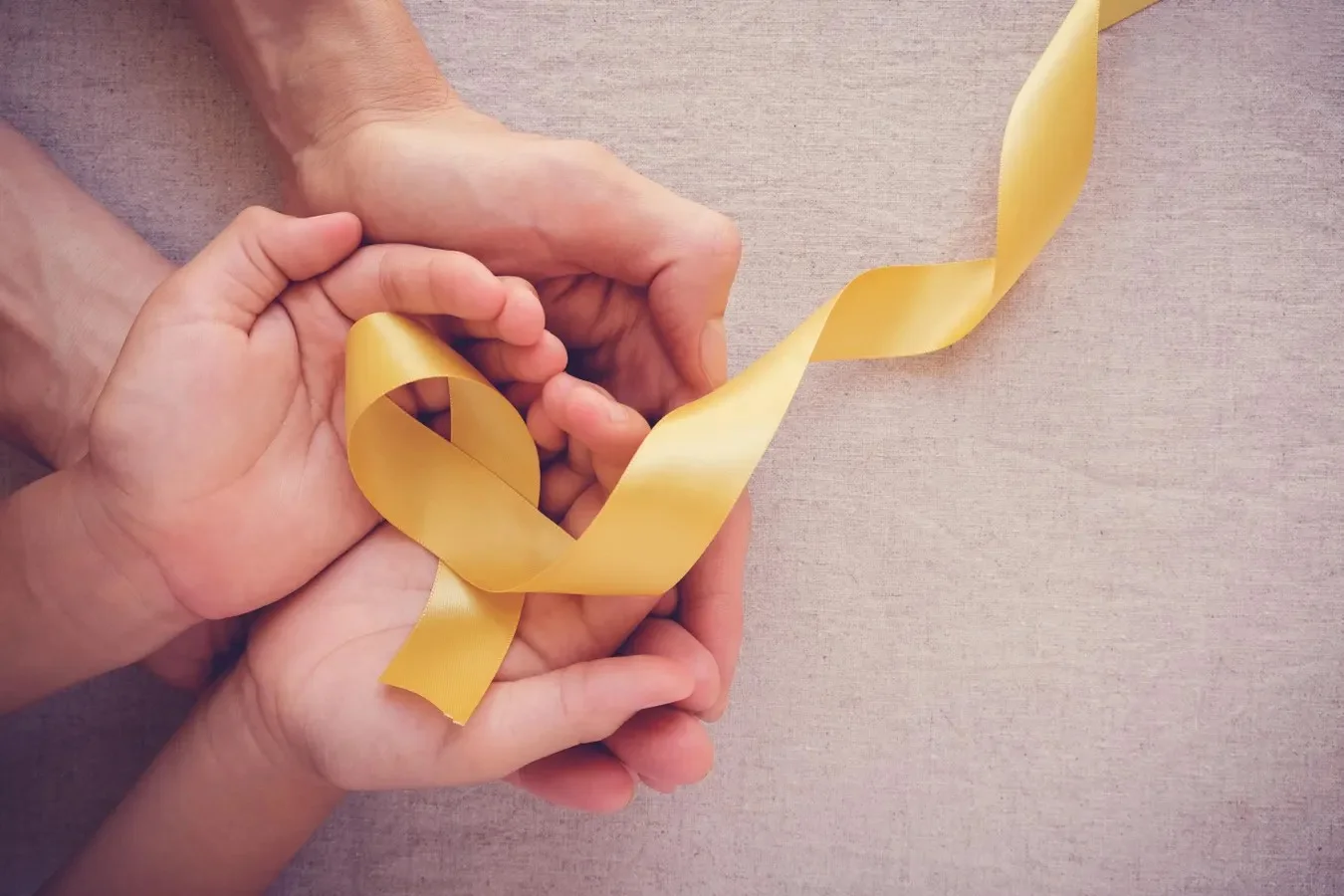 Hands holding a yellow ribbon symbolizing support and awareness