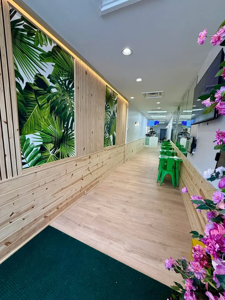 An interior view of a dining space featuring wooden walls, green chairs, and tropical-themed decor.
