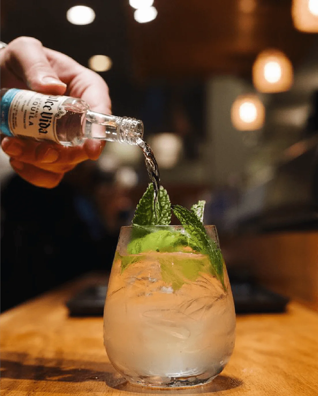 Pouring a bottle into a garnished glass at the table at Mahzu East Windsor, a BYOB restauran