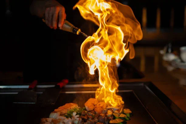 Flaming teppanyaki grill with sizzling seafood and vegetables