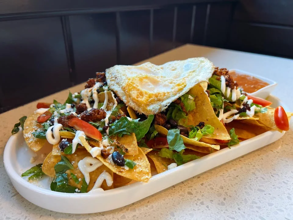 Loaded nachos topped with fried egg and fresh toppings