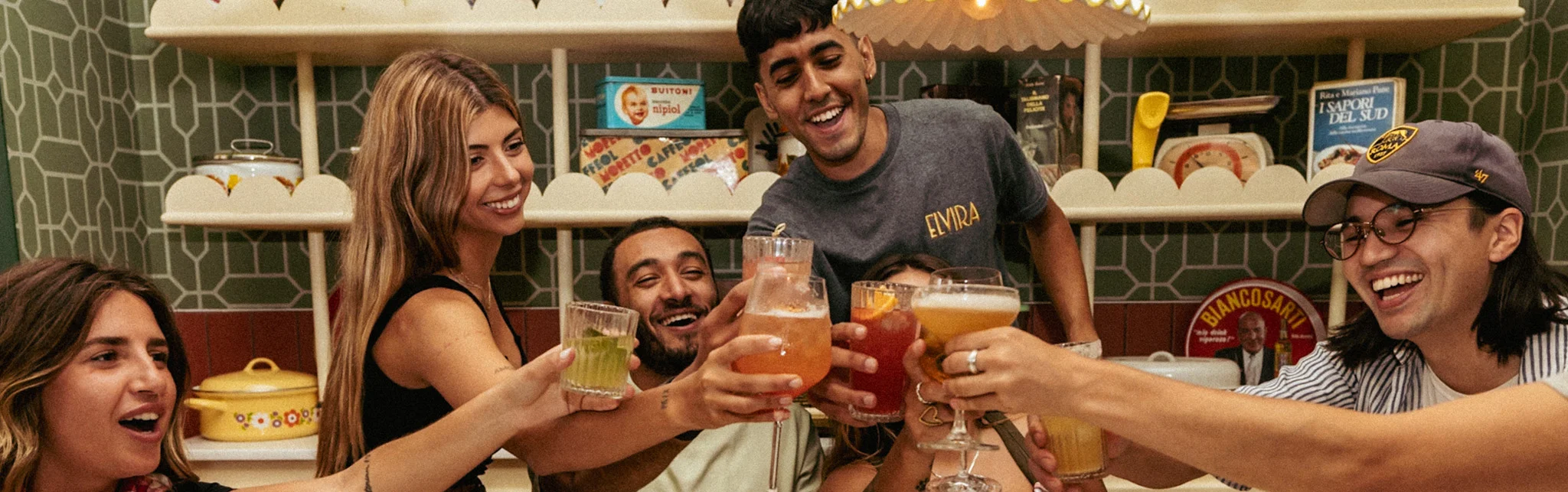 Group of friends toasting with colorful cocktails at a vibrant restaurant
