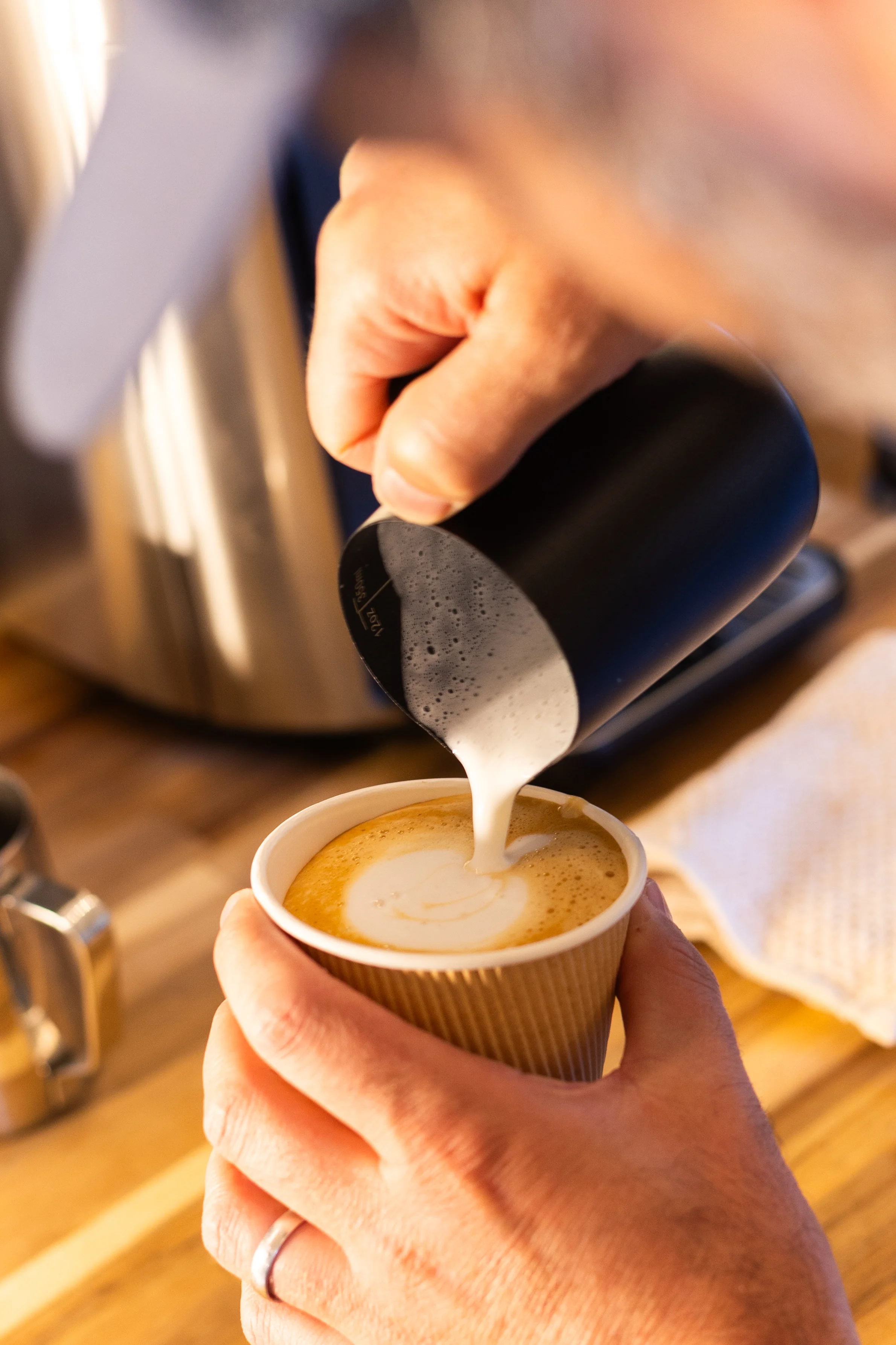 Barista pouring latte art into a coffee cup