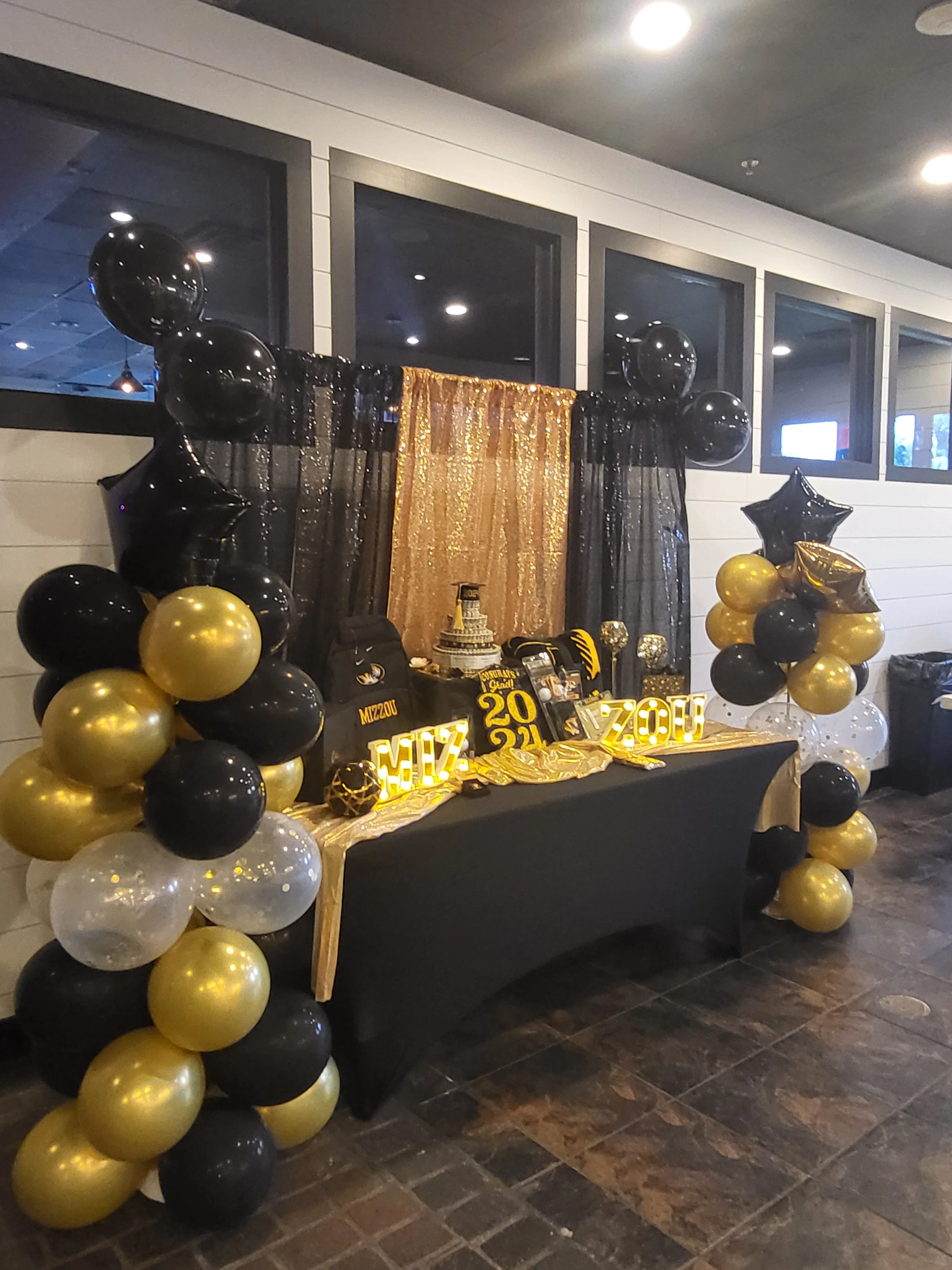 Elegant event decor with black and gold balloons and a festive backdrop