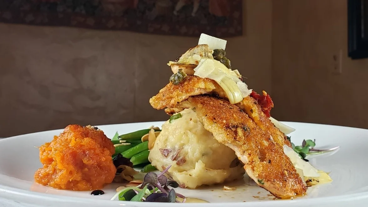 Romano-crusted chicken topped with artichokes, sun-dried tomatoes, and capers over whipped potatoes at Post Oak Grill Downtown Houston.