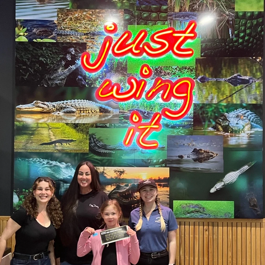team members standing in front of Just Wing It sign