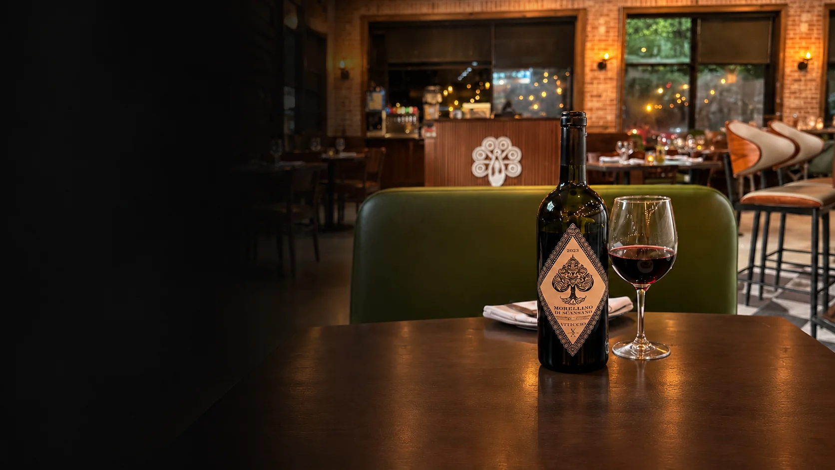 Bottle of red wine and a filled wine glass inside Tavolina44