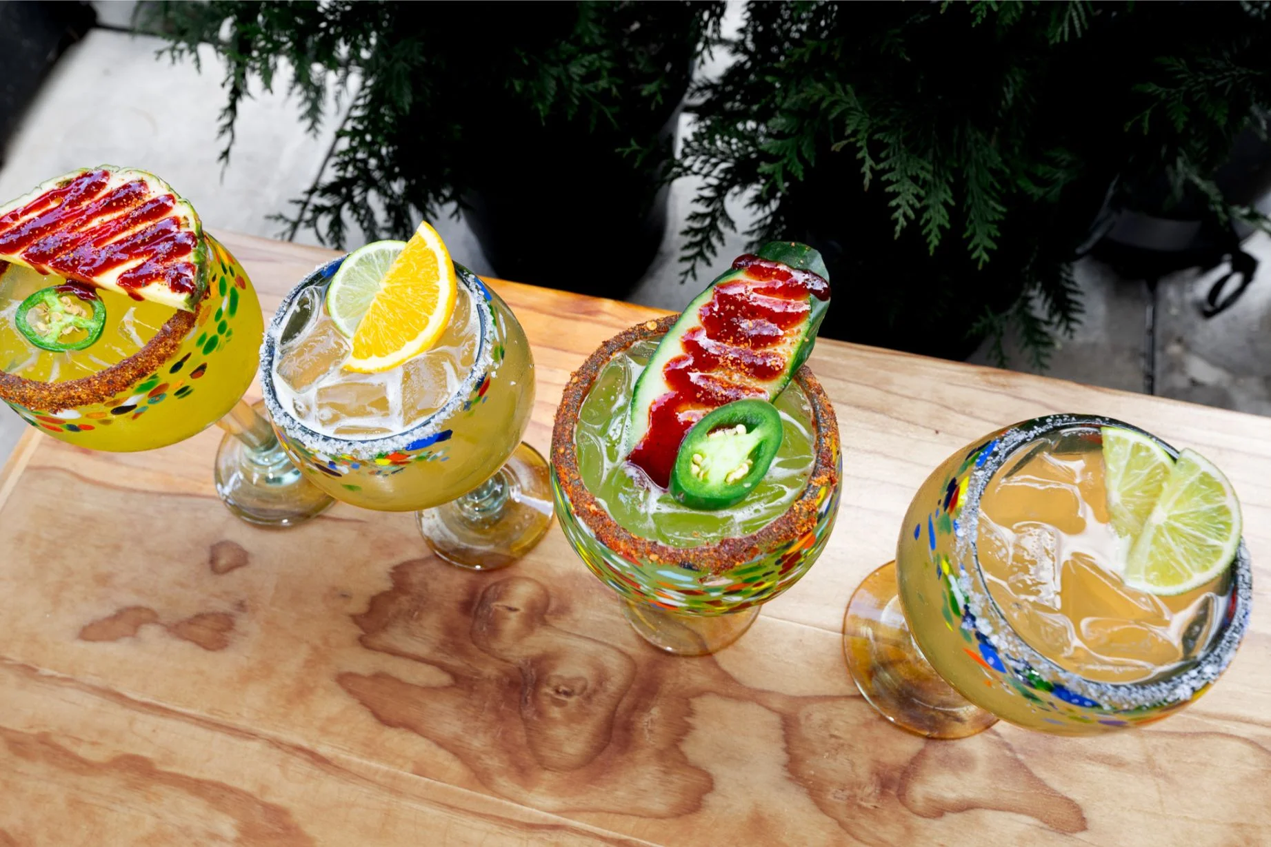 Colorful margaritas with fresh garnishes on a wooden table