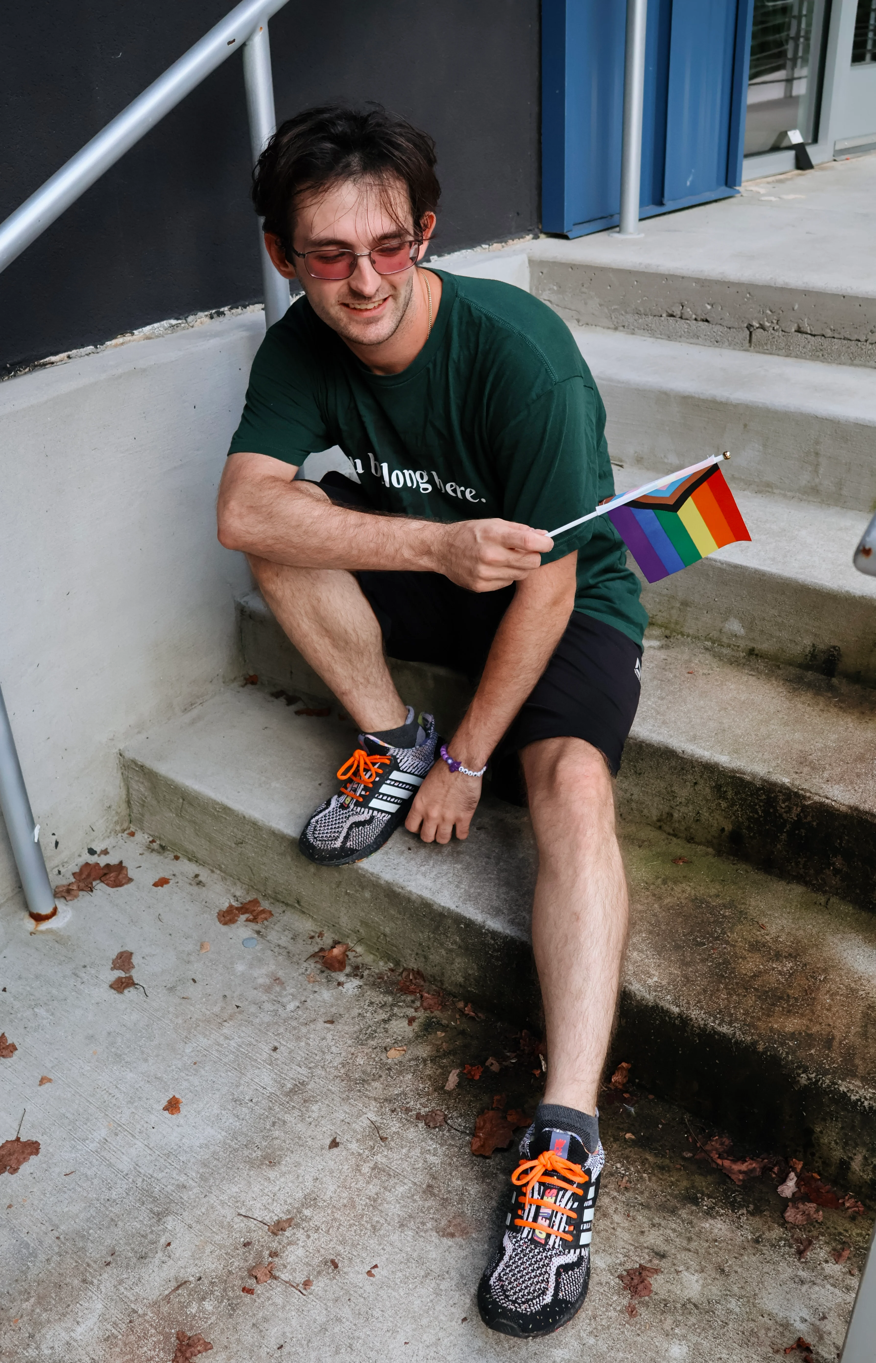 Person holding a rainbow flag beside outdoor concrete steps