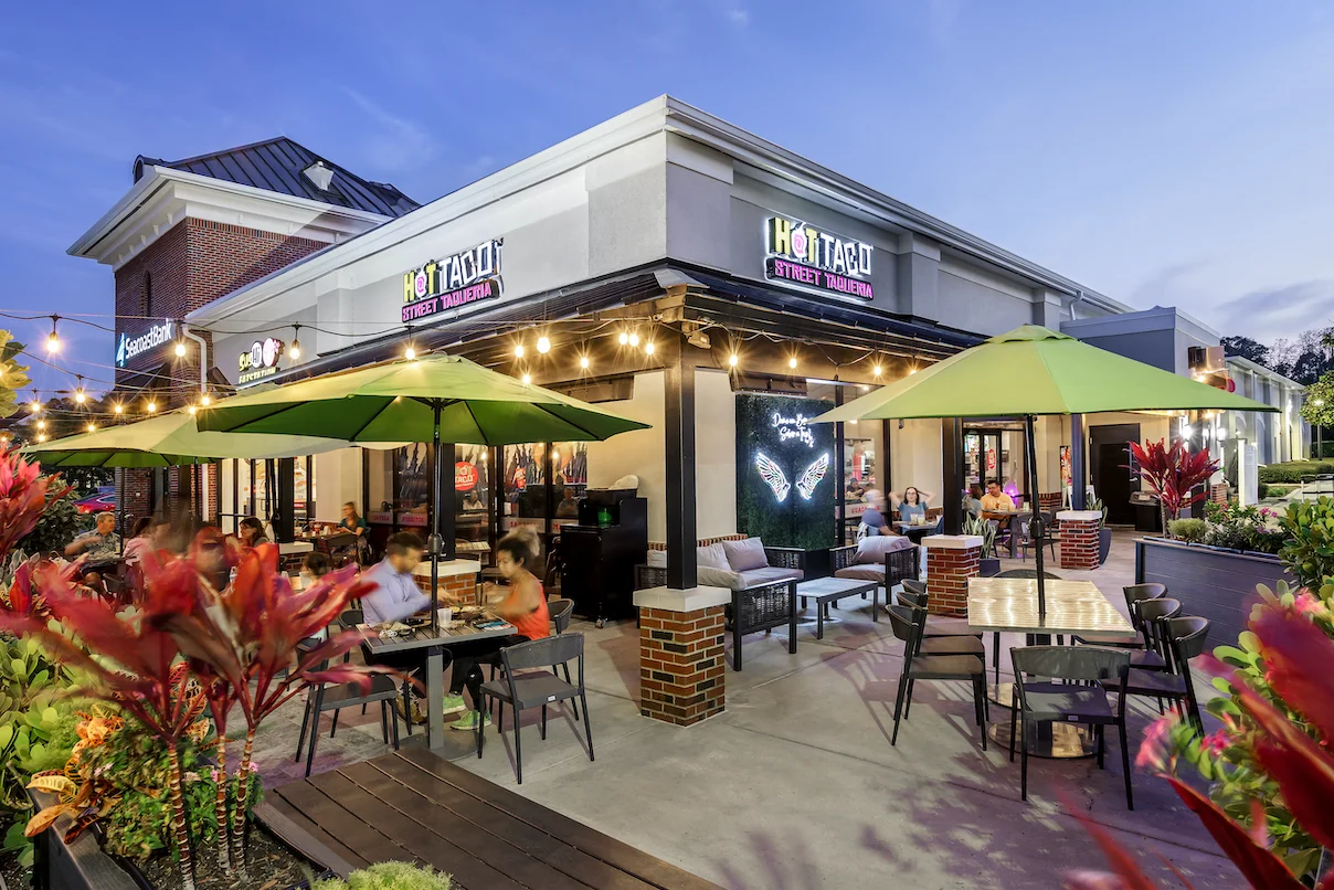 Outdoor dining area of a vibrant taqueria with green umbrellas