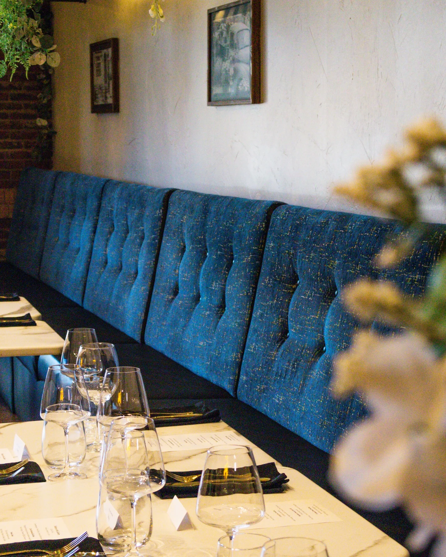 Cozy restaurant interior featuring blue tufted seating and elegant table settings.