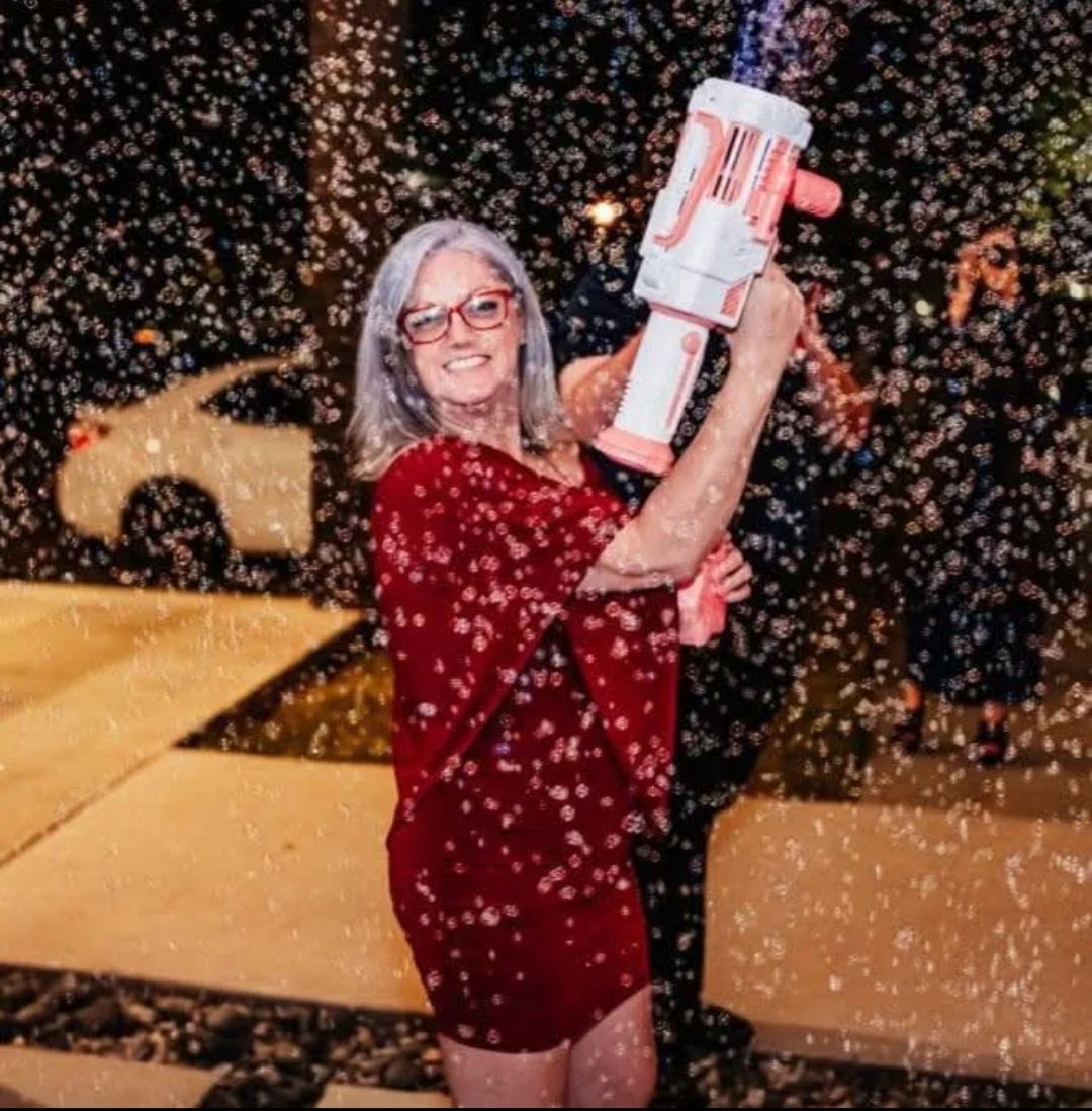 Woman celebrating with a bubble gun at a festive outdoor event