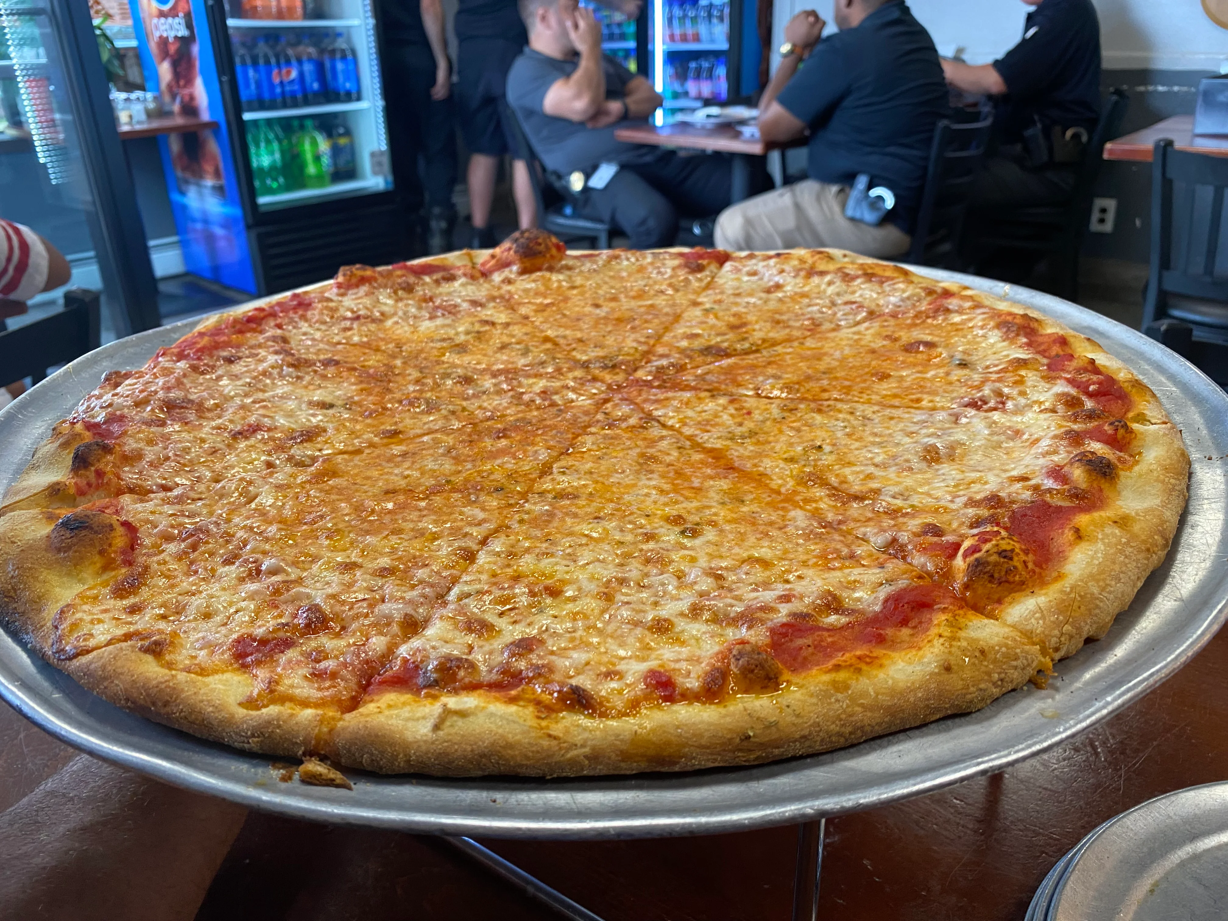 Large cheese pizza served on a metal tray