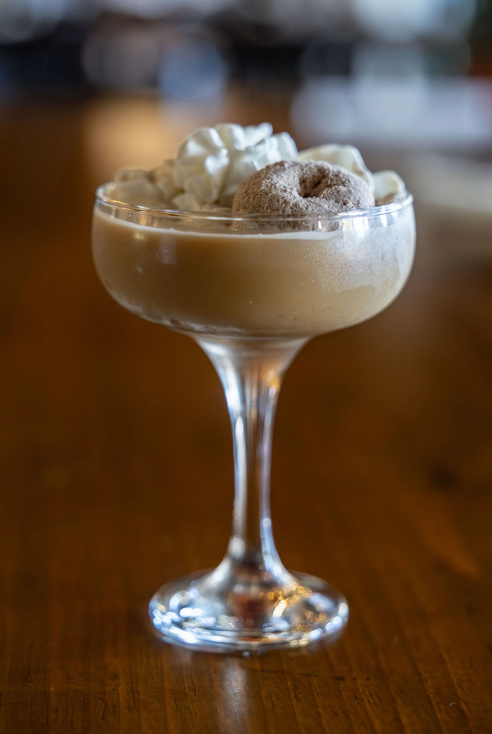 Creamy dessert cocktail topped with whipped cream and a mini donut