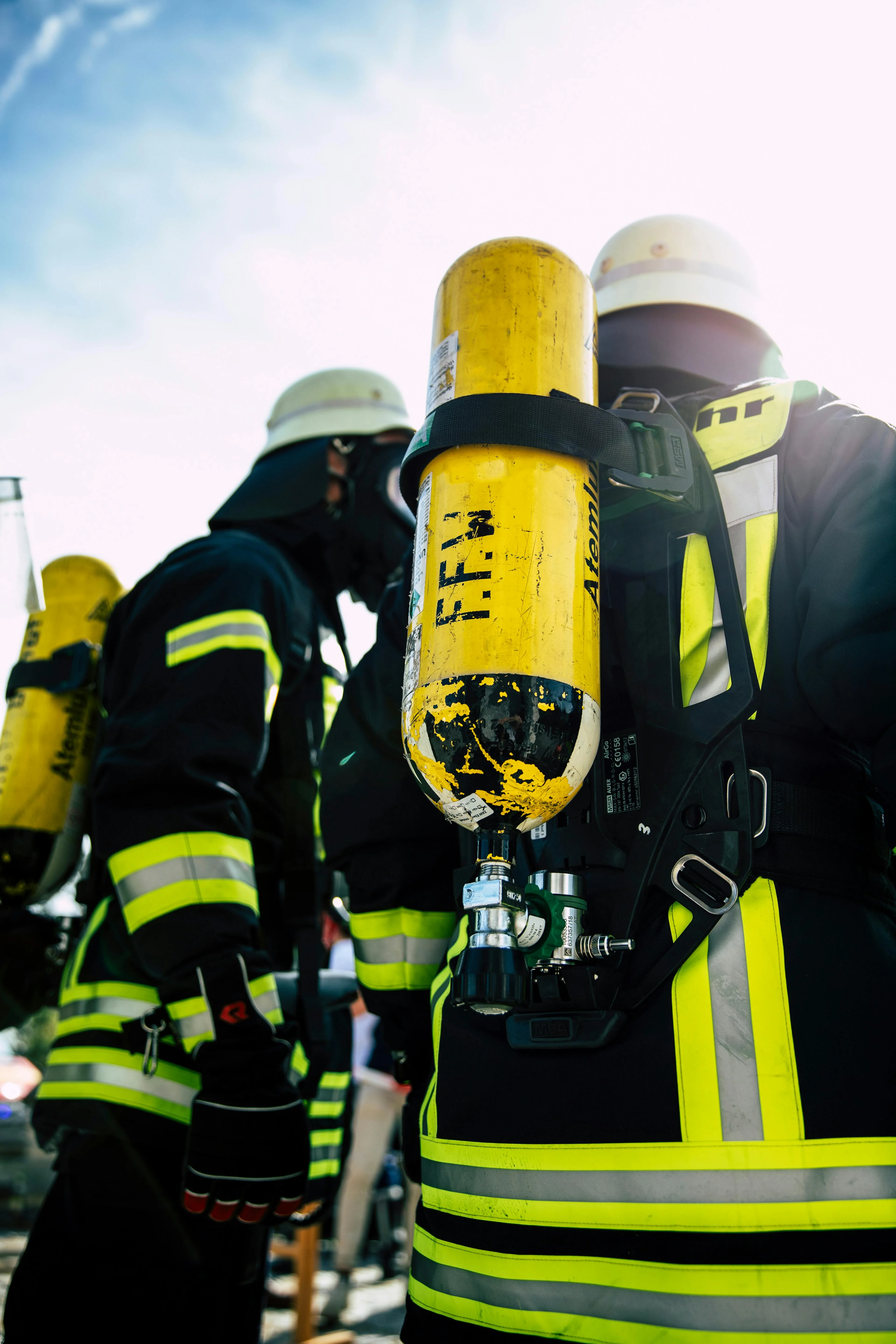 Firefighters in gear preparing for action with oxygen tanks