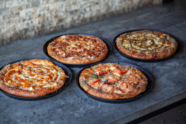 Four delicious pizzas on a rustic table