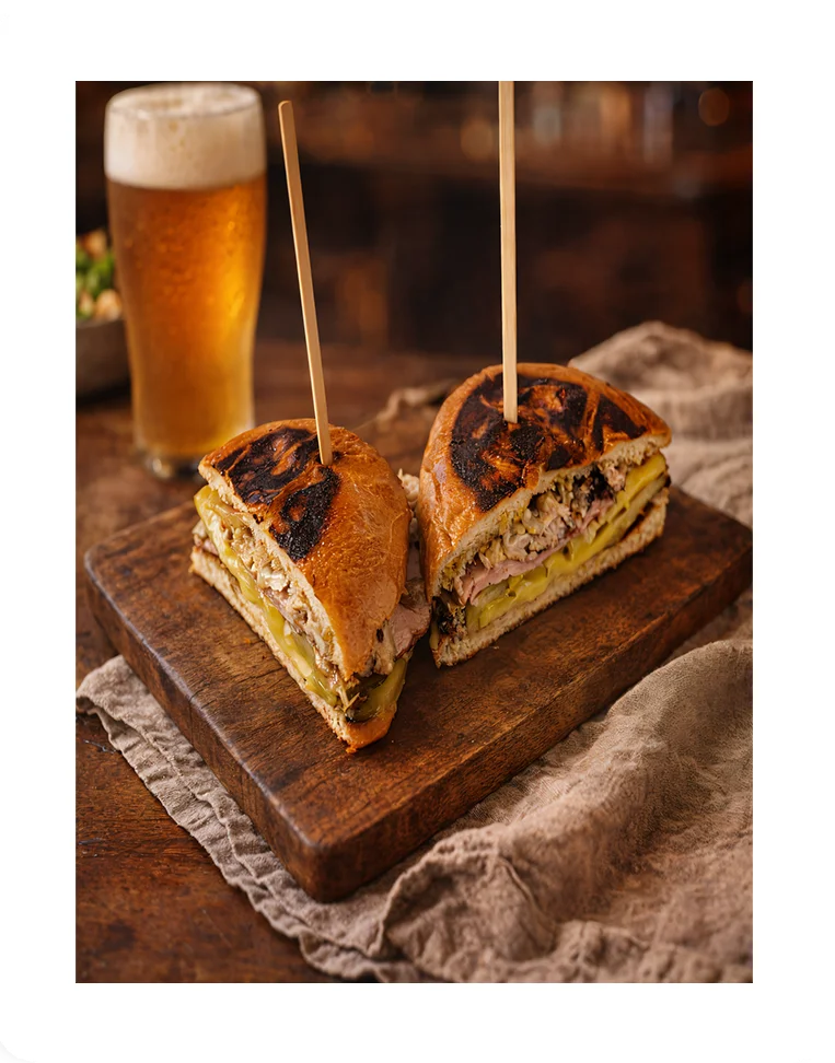 Cuban sandwich with roasted pork and pickles on a wooden board