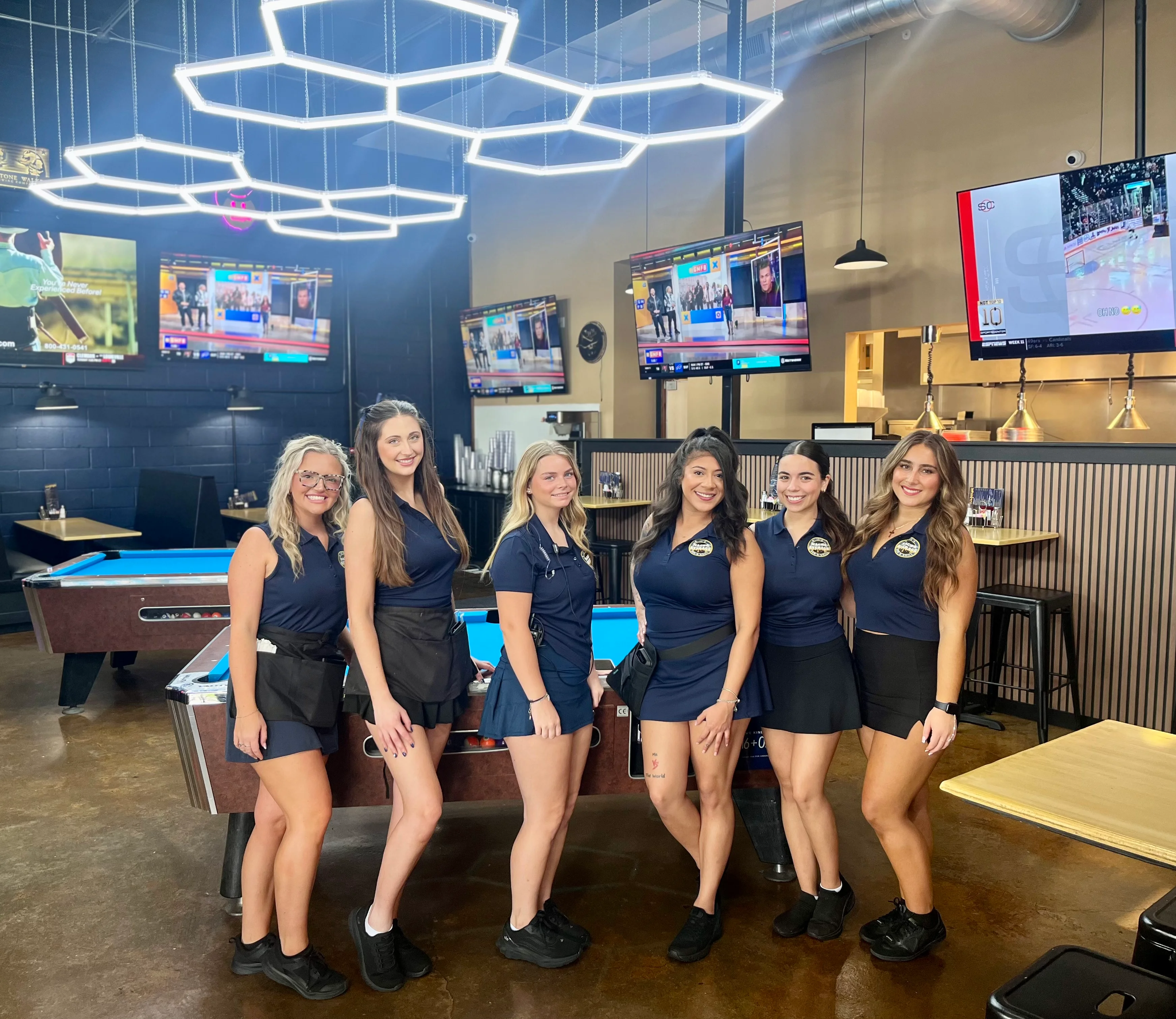 Friendly staff posing in a modern restaurant with pool tables