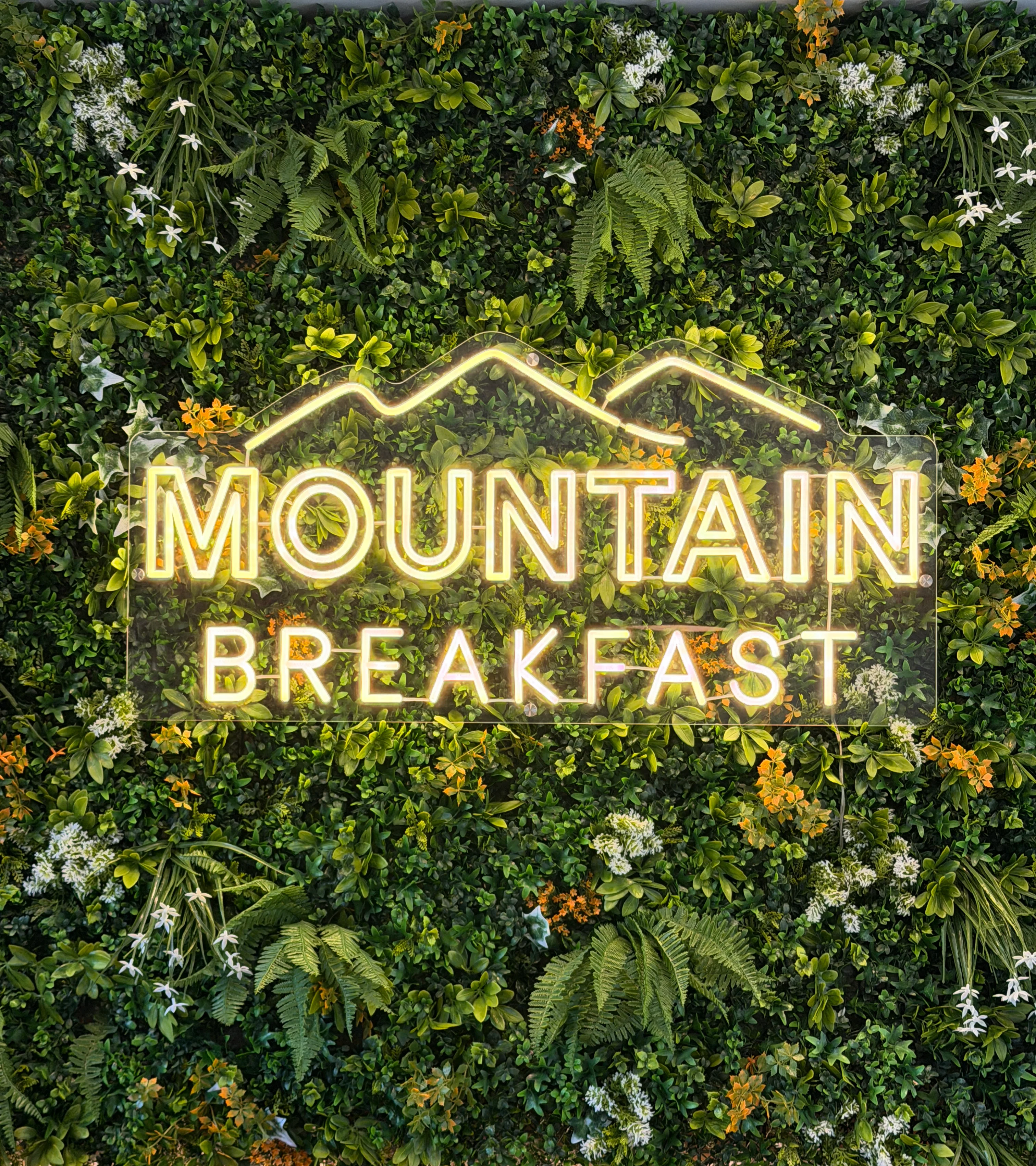 Cozy restaurant sign for Mountain Breakfast surrounded by greenery