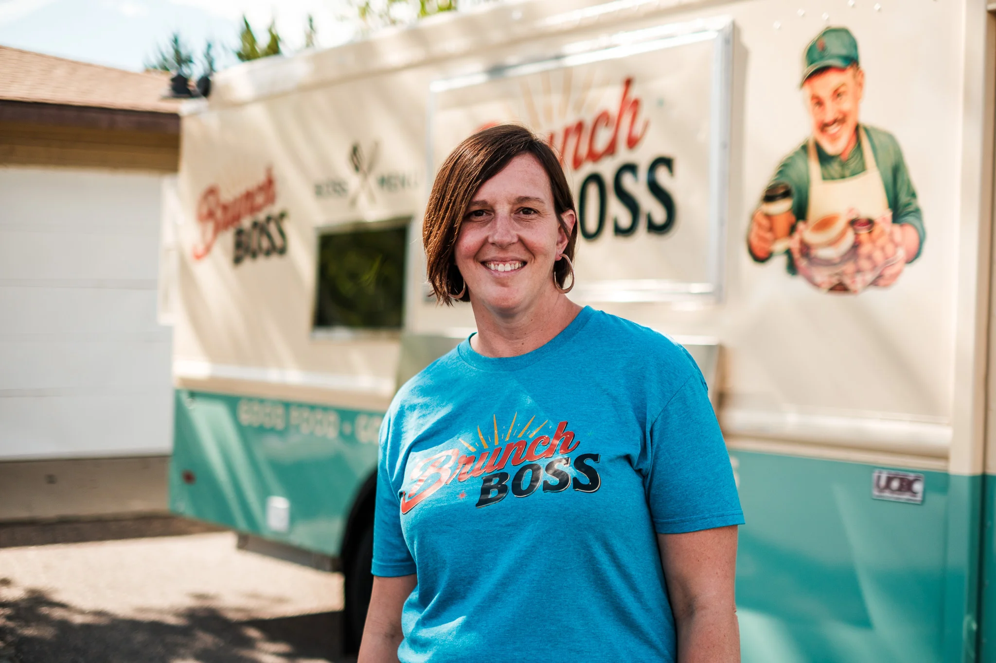 Owner of Brunch Boss food truck smiling in front of vibrant branding