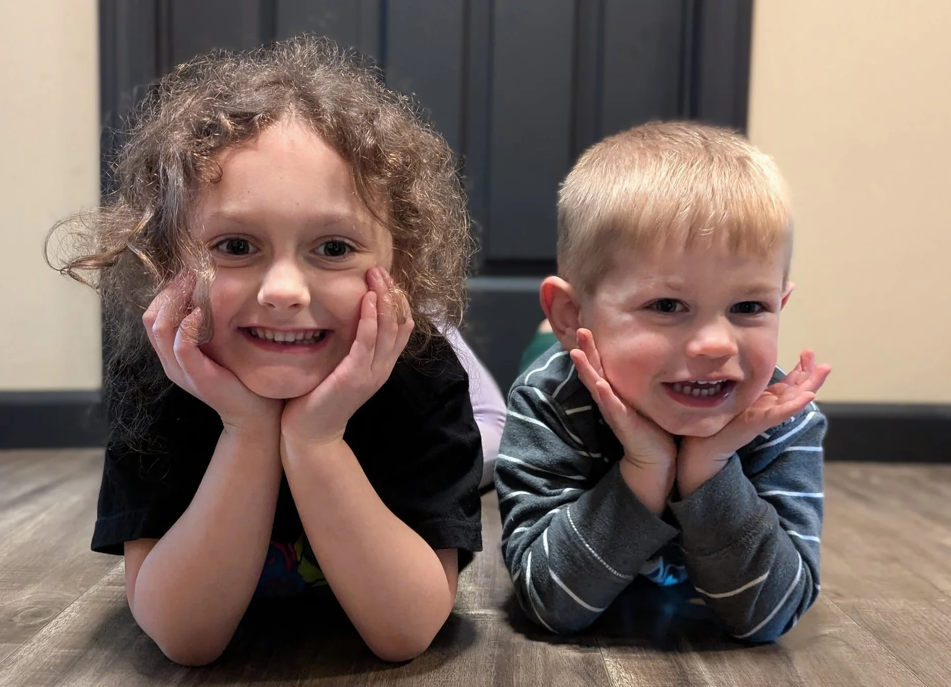 Two children smiling and posing on the floor
