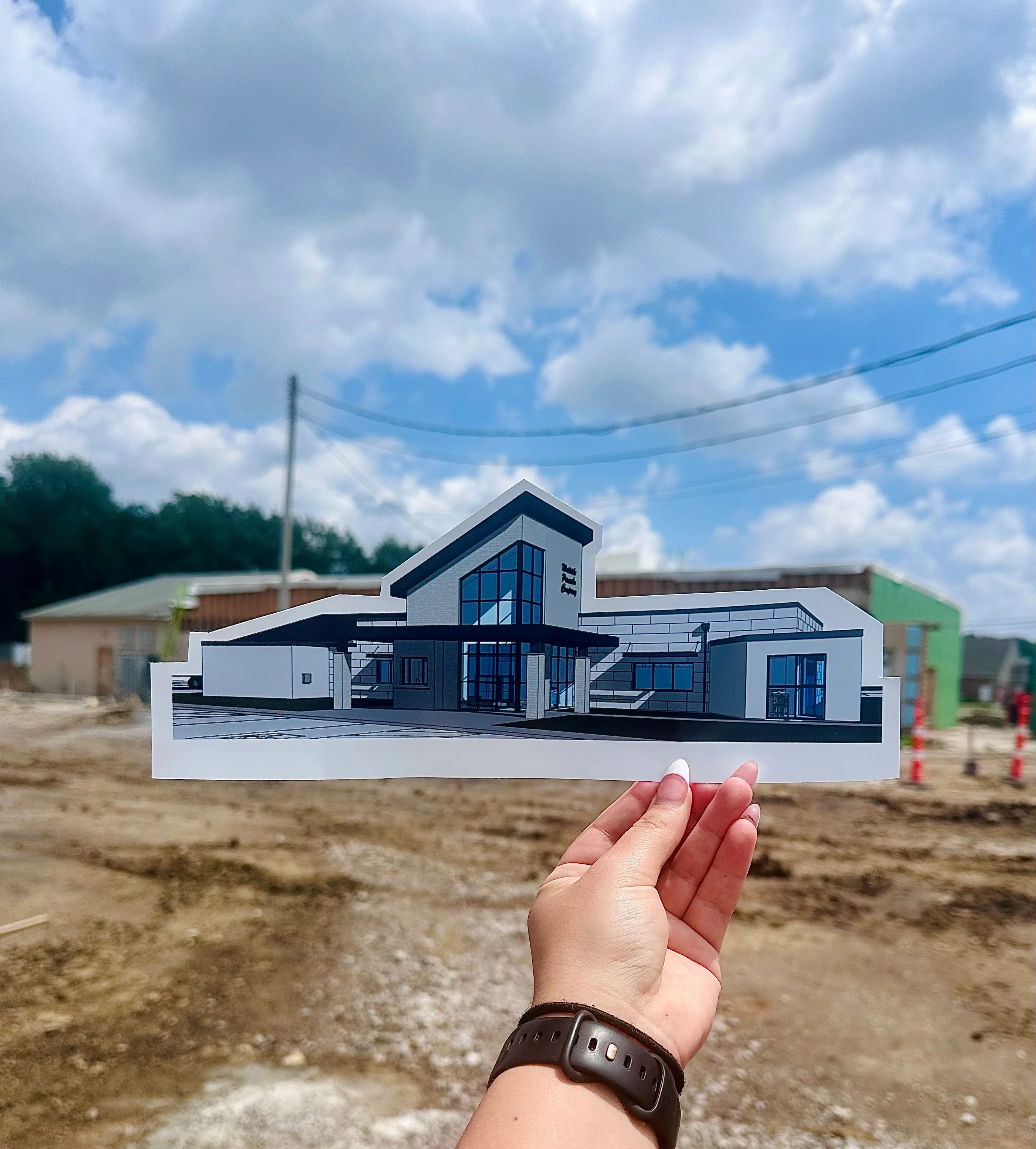 Hand holding architectural rendering of a modern restaurant building
