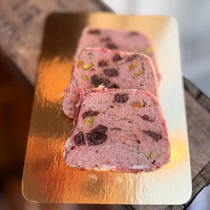 Three slices of a pink meat dish with visible ingredients, presented on a golden tray.