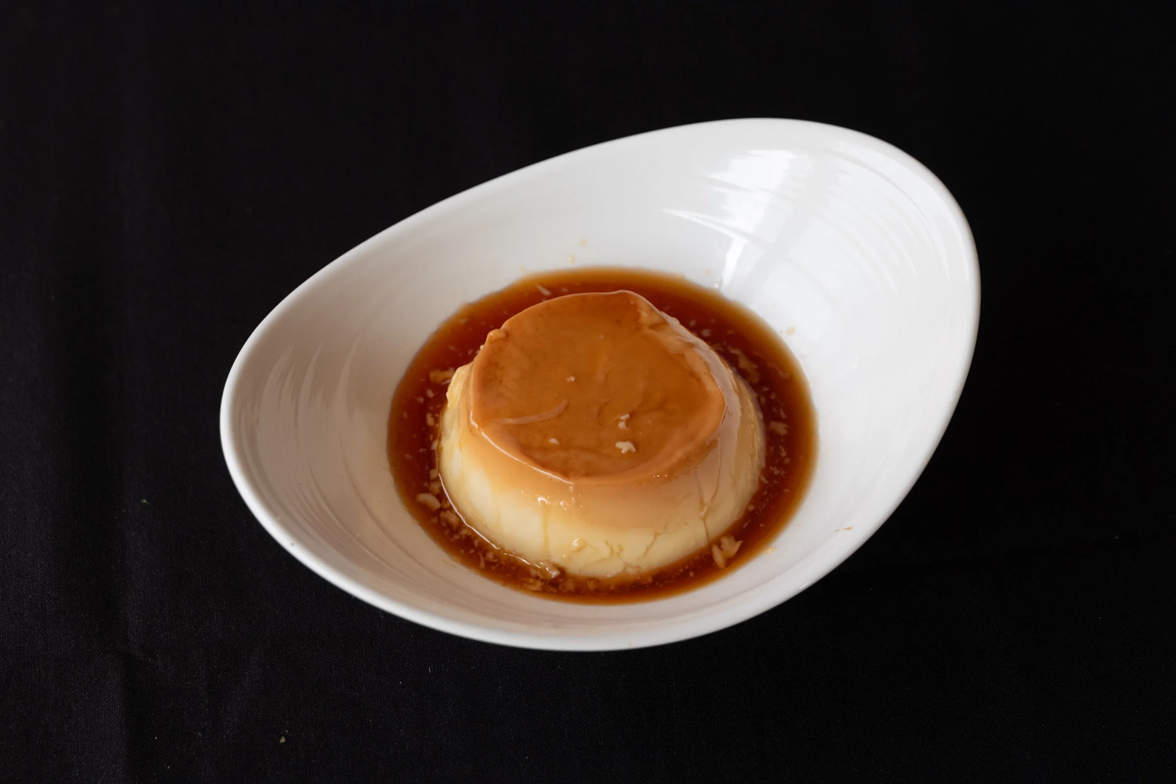 Caramel flan dessert served in a white dish