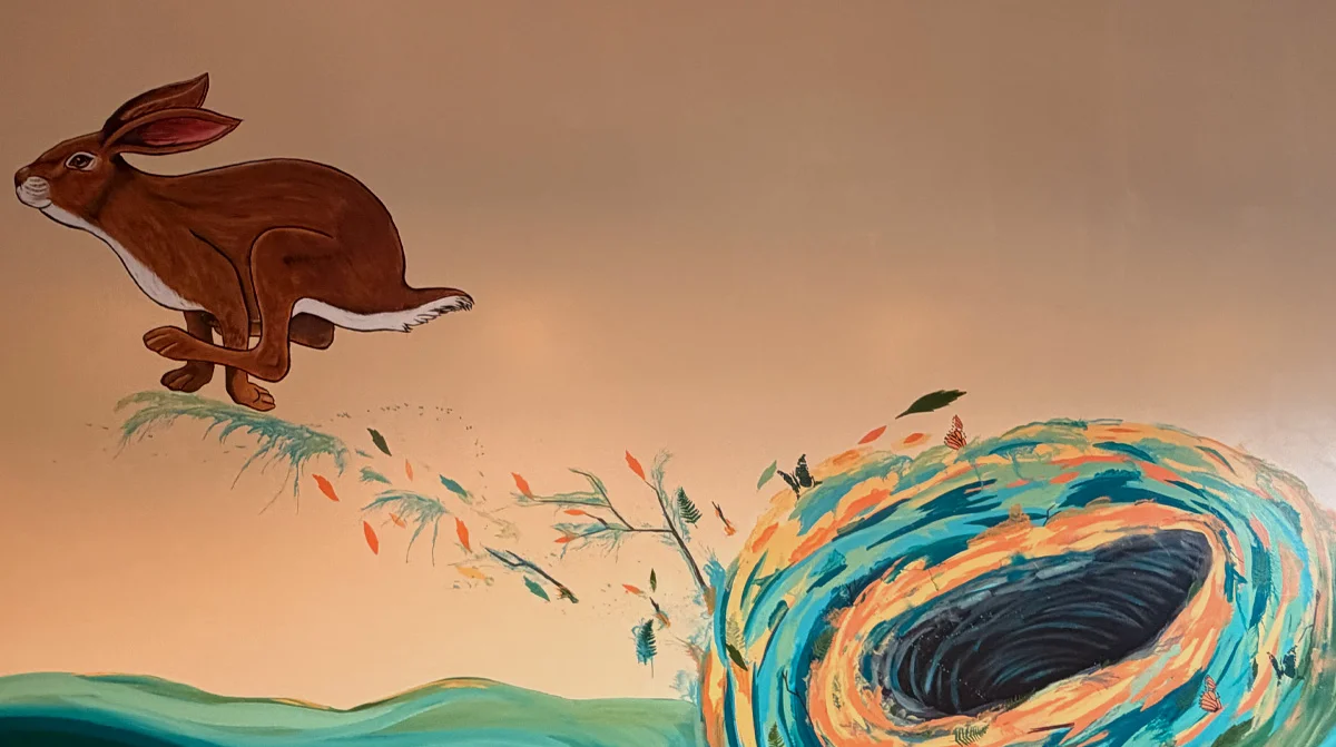 Rabbit running from colorful hole mural in cafe.
